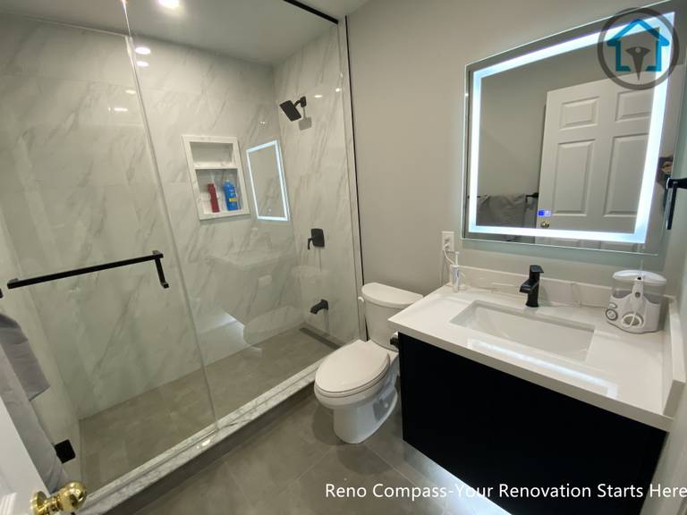 A modern basement bathroom renovation in Markham featuring a glass walk-in shower, large-format wall tiles, LED mirror, and a sleek vanity, designed for durability, comfort, and everyday use.