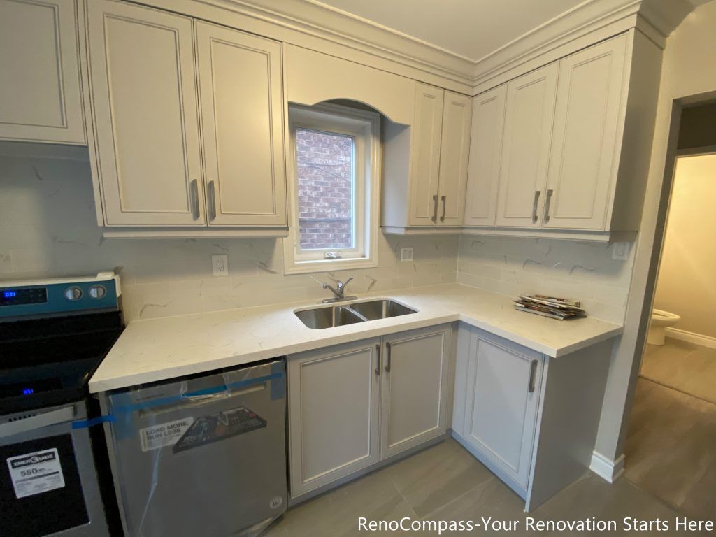 This Mississauga interior renovation features a custom kitchen sink area with shaker-style cabinetry, quartz countertops, and a functional L-shaped layout. The window-above-sink design enhances natural light, while full-height cabinets and clean lines improve storage efficiency and everyday usability. A well-balanced kitchen renovation solution designed for long-term comfort and practicality.