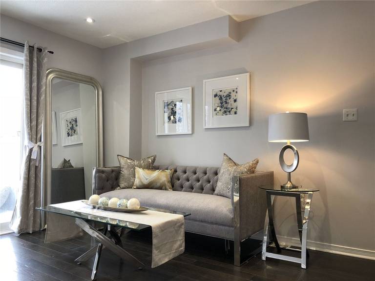 This Toronto interior design pre-sale staging features a cozy and elegant sitting area with a tufted sofa, mirrored accent piece, and modern glass coffee table. Soft lighting, neutral color tones, and carefully selected décor create a welcoming and sophisticated ambiance.