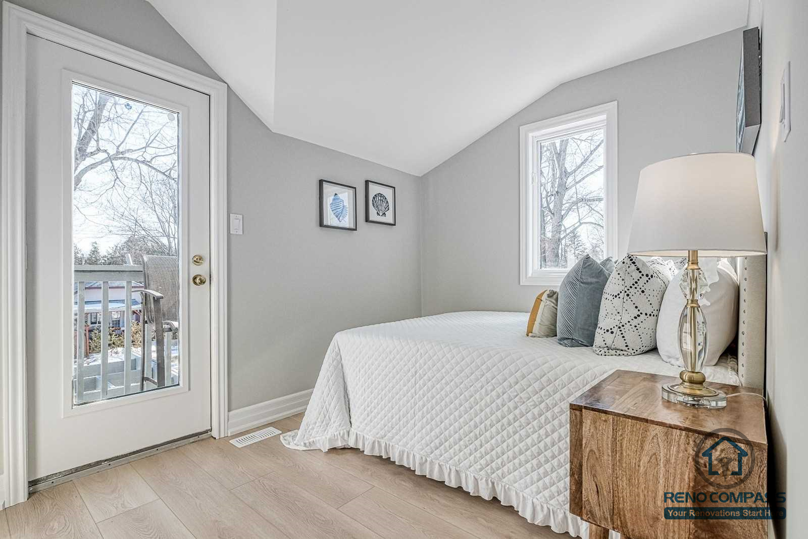 This Georgian interior renovation features a bright secondary bedroom with a balcony door, light wood flooring, and a compact vanity workspace. Soft colors and thoughtful layout create a comfortable and functional private space, completed by a Toronto renovation company.