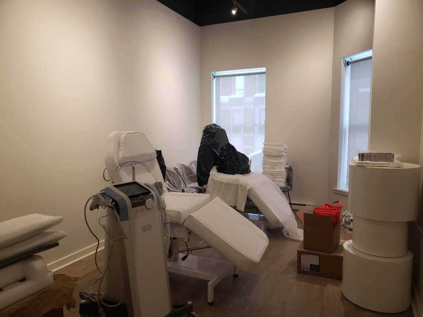 This image shows a fully equipped treatment room within a beauty and massage spa, completed by a professional Toronto renovation company specializing in commercial renovations. The room is designed to accommodate advanced skincare and aesthetic equipment, adjustable treatment beds, and organized storage while maintaining a clean, calming, and professional atmosphere. Natural light from large windows, combined with neutral wall finishes and durable flooring, enhances both client comfort and operational efficiency. This renovation approach is ideal for medical aesthetics clinics, beauty spas, and wellness centers across Toronto and the GTA seeking a functional yet relaxing treatment room environment.