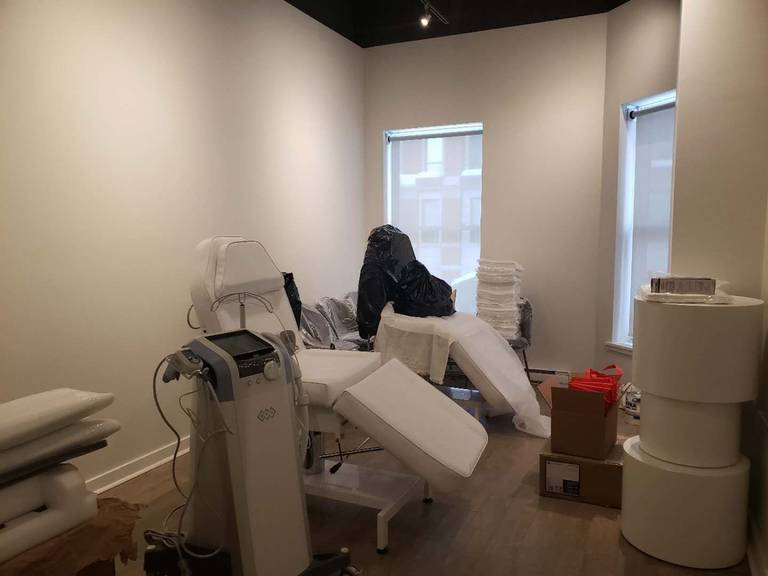 This image shows a fully equipped treatment room within a beauty and massage spa, completed by a professional Toronto renovation company specializing in commercial renovations. The room is designed to accommodate advanced skincare and aesthetic equipment, adjustable treatment beds, and organized storage while maintaining a clean, calming, and professional atmosphere. Natural light from large windows, combined with neutral wall finishes and durable flooring, enhances both client comfort and operational efficiency. This renovation approach is ideal for medical aesthetics clinics, beauty spas, and wellness centers across Toronto and the GTA seeking a functional yet relaxing treatment room environment.