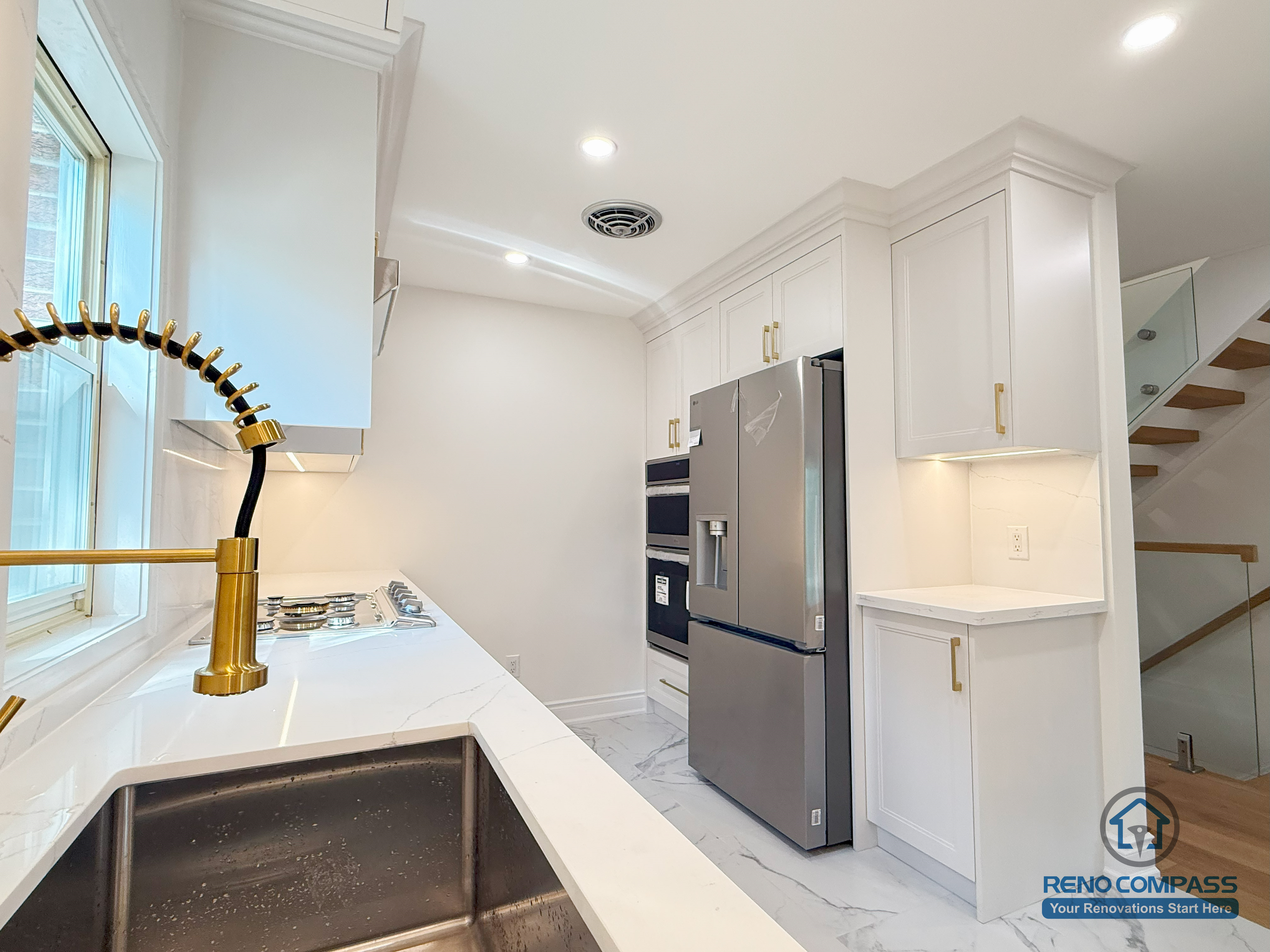 A bright modern kitchen featuring custom white cabinetry, quartz countertops, a gold pull-down faucet, and upgraded stainless steel appliances. The efficient U-shaped layout maximizes workspace and storage, creating a clean and functional cooking environment. Completed in North York by Reno Compass.
这间现代厨房采用定制白色橱柜、石英台面、金色下拉水龙头与全套不锈钢电器。U 型布局让操作台与储物空间大幅增加，整体明亮、干净又实用。本项目由 Reno Compass 在北约克完成。