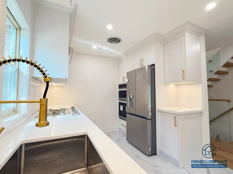 A bright modern kitchen featuring custom white cabinetry, quartz countertops, a gold pull-down faucet, and upgraded stainless steel appliances. The efficient U-shaped layout maximizes workspace and storage, creating a clean and functional cooking environment. Completed in North York by Reno Compass.
这间现代厨房采用定制白色橱柜、石英台面、金色下拉水龙头与全套不锈钢电器。U 型布局让操作台与储物空间大幅增加，整体明亮、干净又实用。本项目由 Reno Compass 在北约克完成。