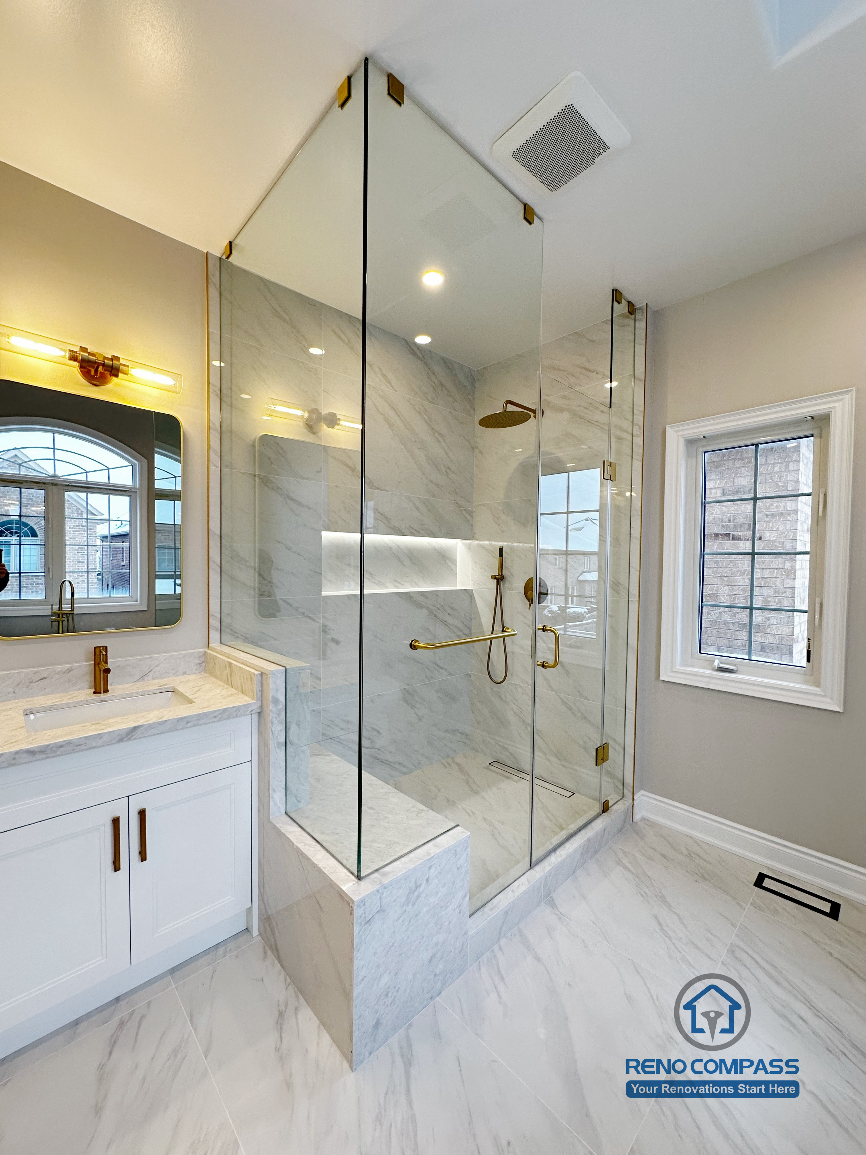Elegant walk-in shower design in a Vaughan primary bathroom renovation, featuring floor-to-ceiling frameless glass panels, marble-look tile walls, built-in shower bench, recessed niche lighting, and gold shower fixtures. Completed by a trusted Toronto renovation company with a focus on clean lines, natural light, and modern luxury.