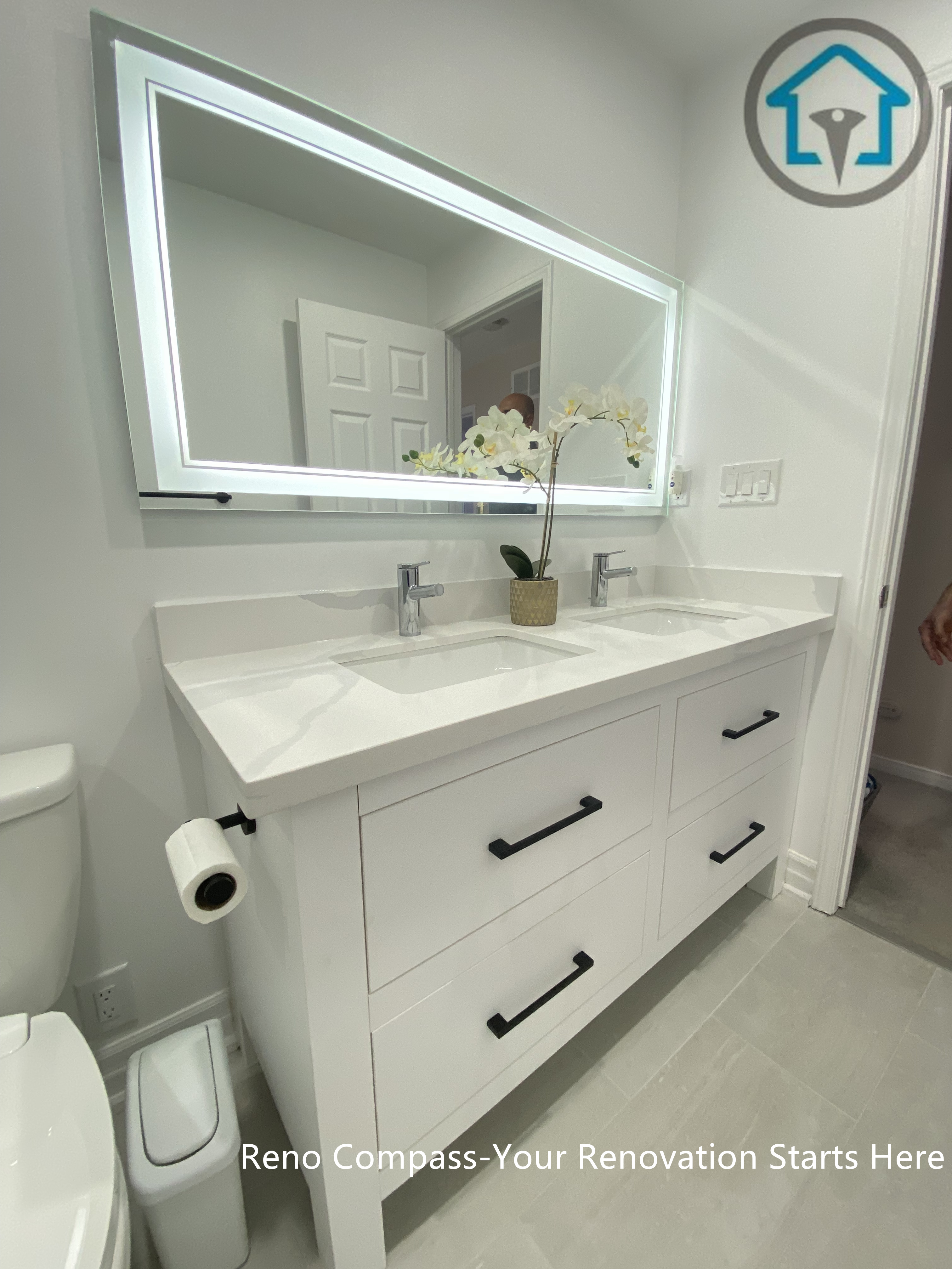 This Pickering bathroom renovation features a custom double vanity designed for both storage efficiency and everyday comfort. Clean-lined white cabinetry is paired with matte black handles for subtle contrast, while the integrated LED mirror provides even lighting and visual depth. The layout keeps the space organized and functional without compromising on a clean, modern aesthetic.
