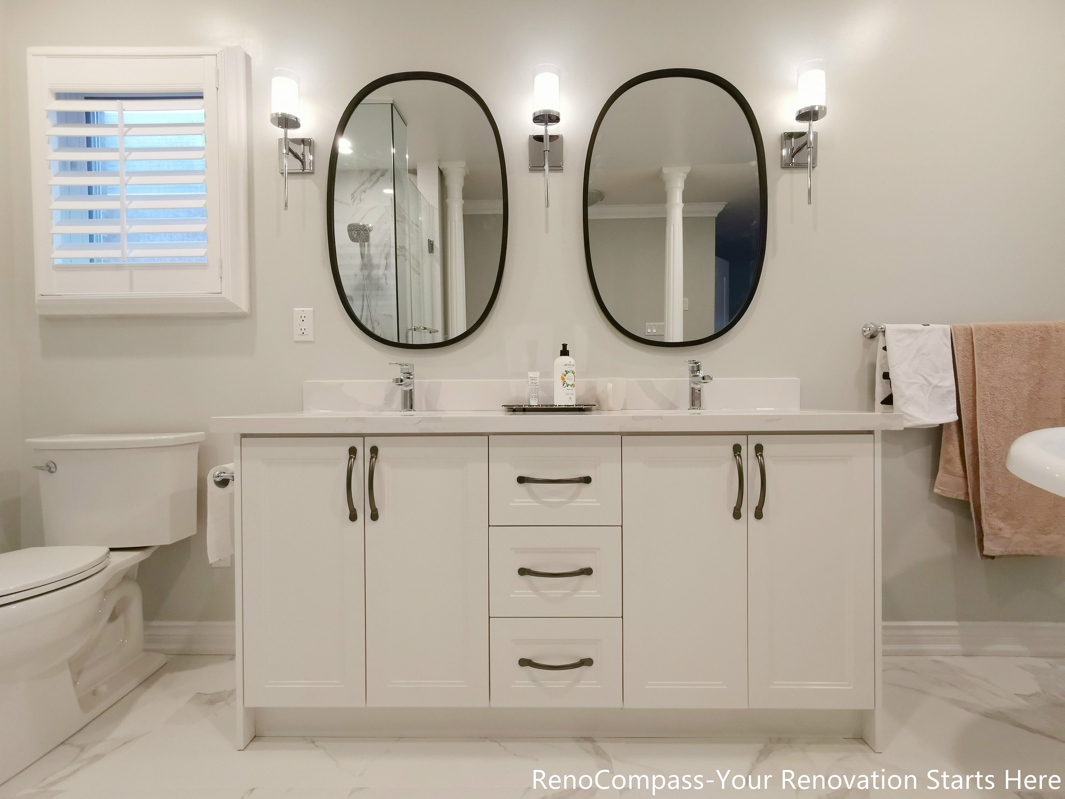 This image highlights a custom double vanity completed as part of an Oakville interior renovation. The design features two oval mirrors positioned symmetrically above the vanity, creating balance and visual clarity. The cabinet hardware and mirror frames are finished in the same tone, ensuring a cohesive and refined look throughout the space. Clean-lined cabinetry and a generous countertop provide practical storage and everyday functionality, while the coordinated finishes elevate the bathroom with a subtle, understated sense of luxury.
