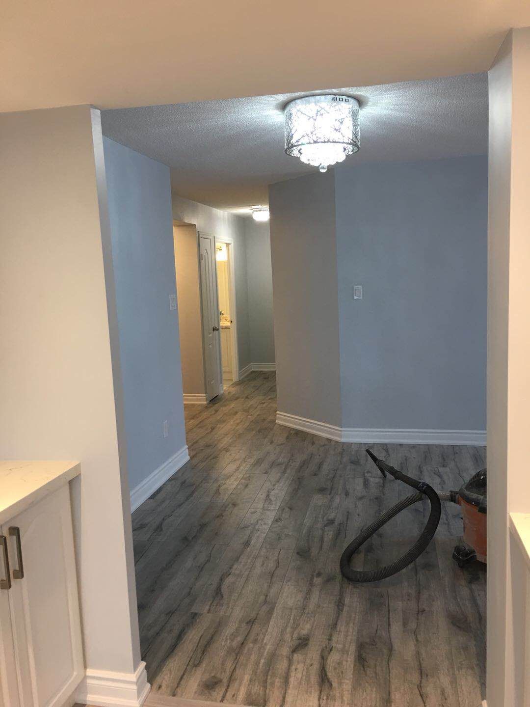 This Toronto interior renovation project showcases a refreshed hallway space featuring durable wood-look flooring, newly painted walls, updated trim, and modern ceiling lighting. The renovation improves brightness and flow between rooms while creating a clean and cohesive look for the home's interior layout.