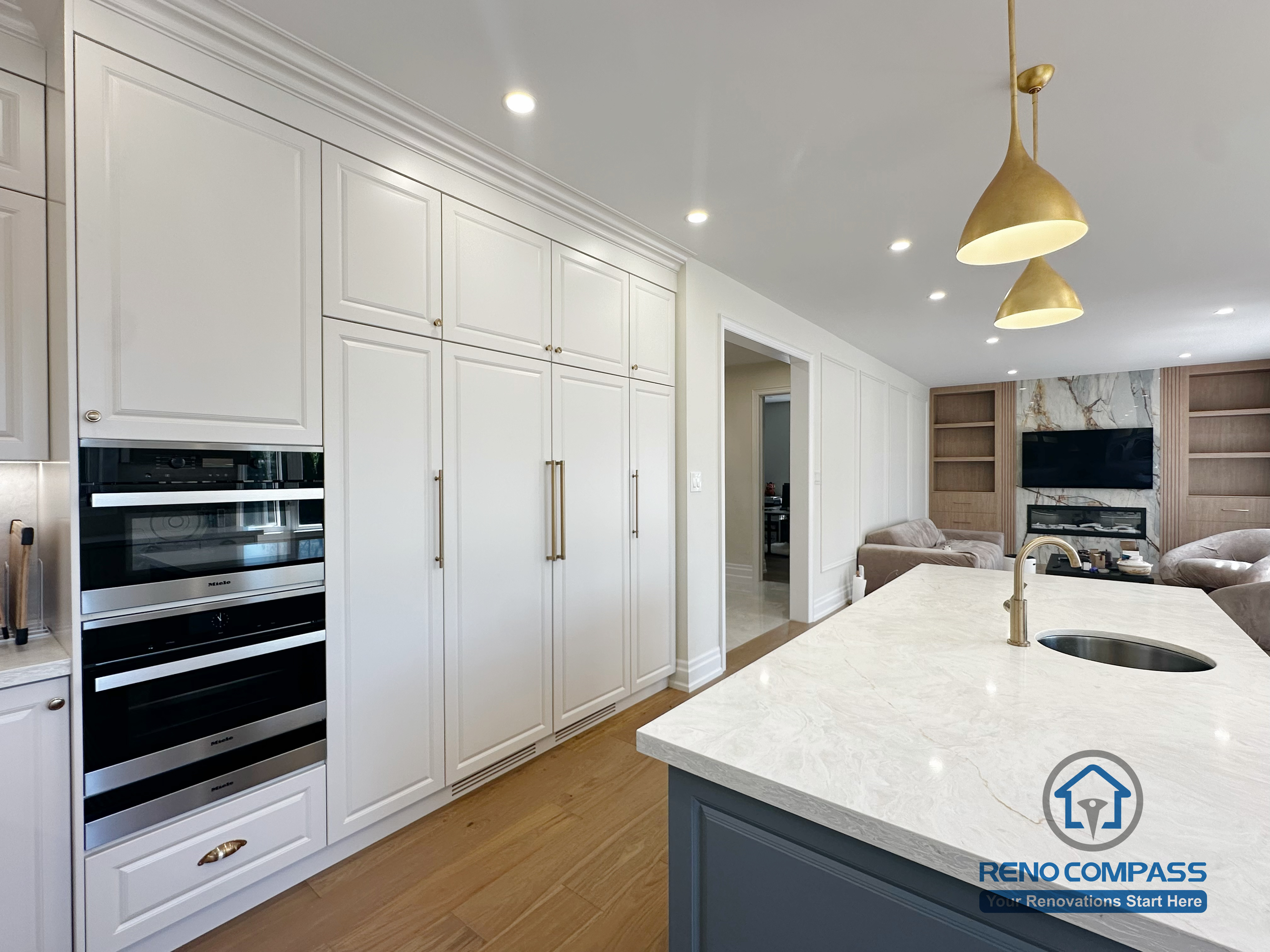 This North York kitchen renovation features full-height custom cabinetry with integrated built-in ovens, maximizing storage while maintaining a clean and seamless appearance. The extended island connects the kitchen to the living area, supporting smooth circulation and visual continuity in this thoughtfully planned renovation completed by Reno Compass.