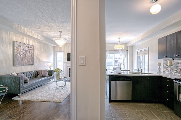 This open-concept interior highlights the seamless connection between the modern living room and upgraded kitchen space. Featuring dark hardwood flooring, contemporary cabinetry, quartz countertops, and elegant chandelier lighting, the layout enhances both visual flow and everyday functionality. The balanced mix of textures and neutral tones creates a cohesive and sophisticated home environment. Completed by a professional Toronto renovation company, this renovation showcases thoughtful space planning and modern interior design tailored for comfortable family living.