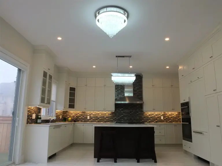 This Kleinburg interior renovation showcases a bright modern kitchen with full-height white cabinetry, a large central island, custom tile backsplash, and elegant pendant lighting. Designed to maximize storage, lighting, and workspace, the kitchen combines functionality with contemporary style, completed by a professional Toronto renovation company.