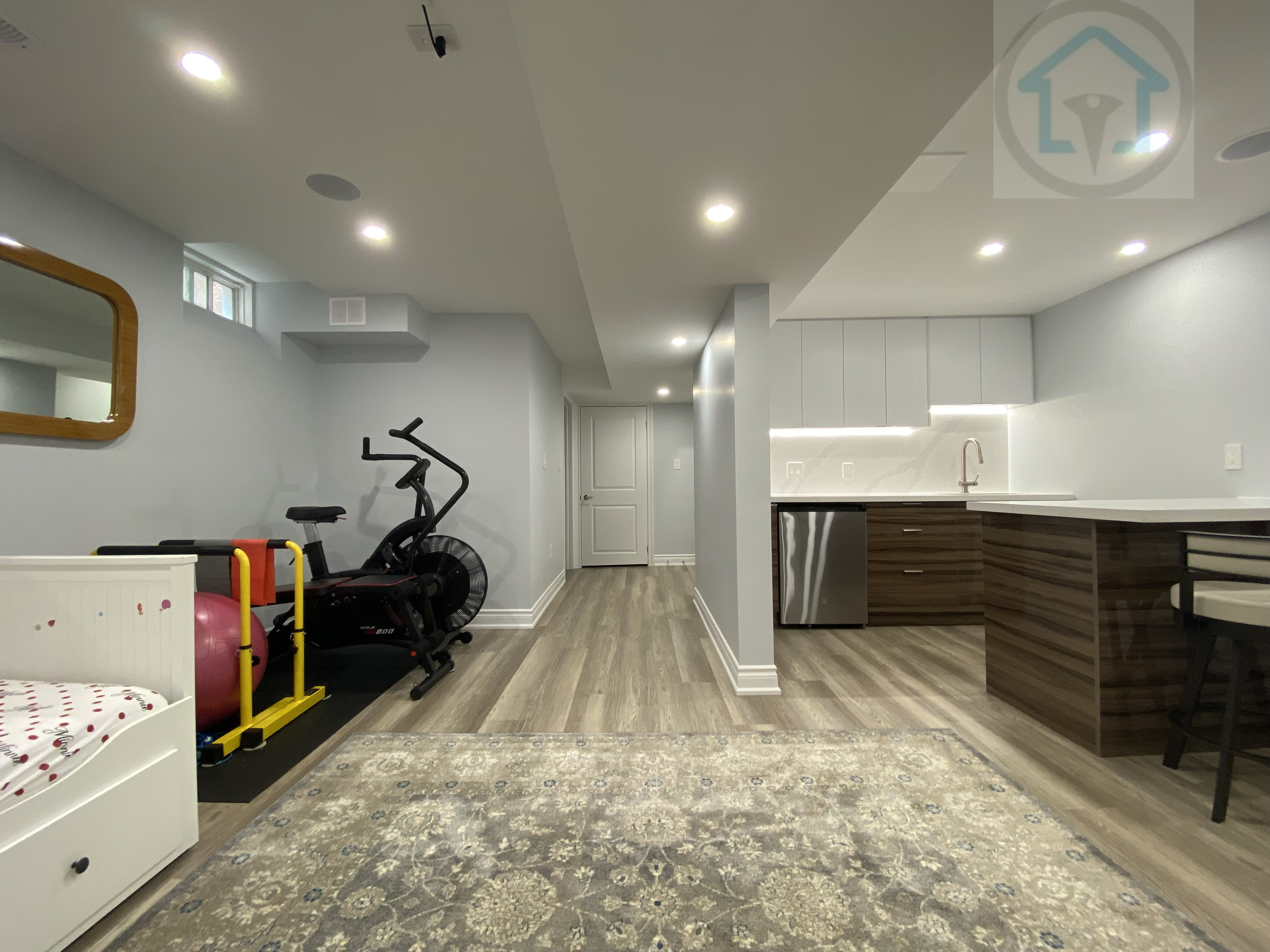 This Vaughan basement renovation features a bright open-concept layout that connects the living area, kitchen, and multi-purpose zones. Recessed lighting, continuous flooring, and a clean ceiling design improve spatial flow and comfort. The modern basement kitchen includes integrated cabinetry and durable finishes, supporting everyday family use and flexible activities.