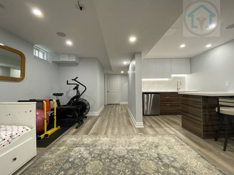 This Vaughan basement renovation features a bright open-concept layout that connects the living area, kitchen, and multi-purpose zones. Recessed lighting, continuous flooring, and a clean ceiling design improve spatial flow and comfort. The modern basement kitchen includes integrated cabinetry and durable finishes, supporting everyday family use and flexible activities.