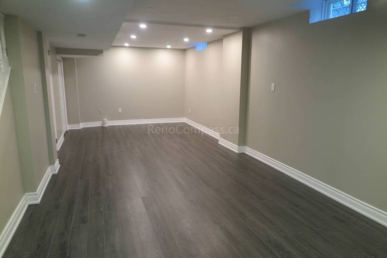 This Markham basement renovation features a clean and modern open-concept space with newly installed dark wood flooring, recessed LED pot lights, and fresh neutral wall finishes. The layout is designed to create a bright and functional lower-level living area suitable for entertainment, home office, or family use. Completed by Reno Compass, a professional renovation contractor specializing in basement finishing and full interior renovations across Markham and the Greater Toronto Area.