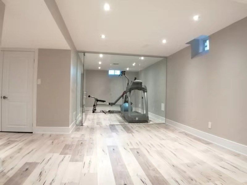 This Richmond Hill interior partial renovation showcases a modern basement home gym upgrade featuring a full glass partition wall, recessed ceiling lighting, and durable light-tone flooring. The space was redesigned to create a bright and functional fitness area while maintaining a clean, contemporary interior style. This basement renovation enhances usability and adds lifestyle value to the home, providing a dedicated workout space with improved lighting, layout, and finishing details. Completed by Reno Compass, this project highlights professional interior remodeling services across Richmond Hill and the Greater Toronto Area.