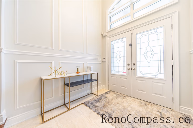 This Richmond Hill entire house interior renovation features a bright and elegant foyer with custom wall paneling, modern double entry doors, and refined decorative lighting. Clean lines, neutral tones, and high-end finishes create a welcoming and sophisticated entrance that reflects the quality craftsmanship of a professional Toronto renovation company. Designed to enhance natural light, functionality, and timeless style, this entryway sets the tone for the full home renovation.
