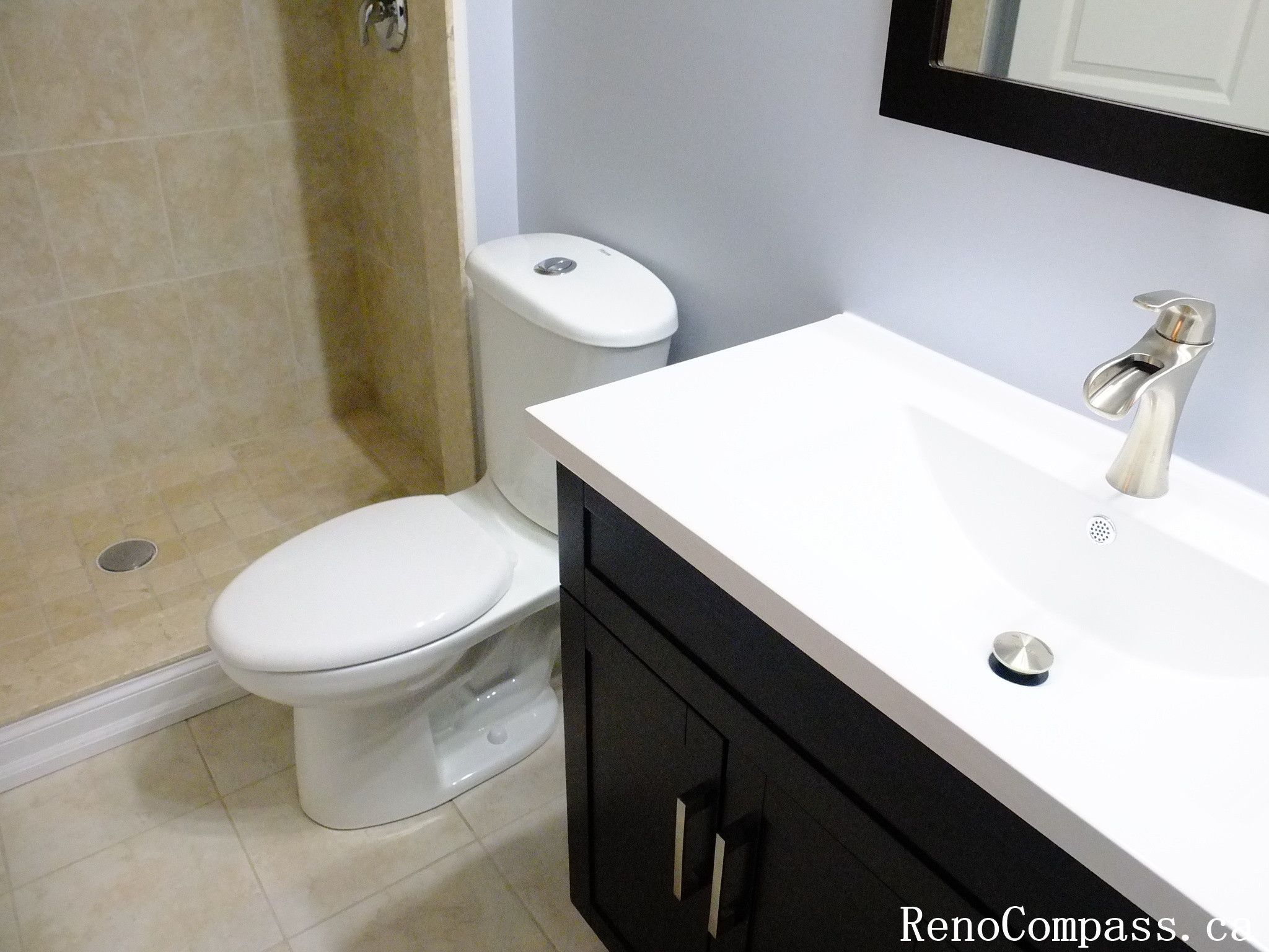 Elegant powder room renovation in Richmond Hill featuring a dark wood vanity with marble countertop, modern toilet installation, and beige ceramic tile flooring. A stylish blend of functionality and luxury by RenoCompass.ca interior renovation experts.