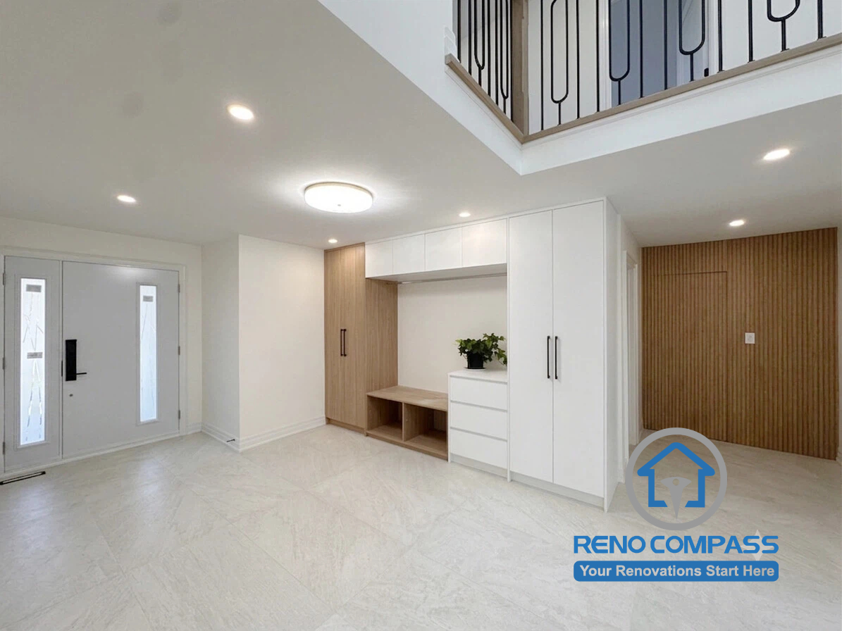 A modern entryway featuring a custom mudroom with built-in storage, bench seating, and floor-to-ceiling cabinetry as part of a luxury home renovation in Markham, Ontario. This bright double-height foyer combines functional organization, contemporary interior design, and premium craftsmanship, creating a welcoming and practical entrance by Reno Compass.