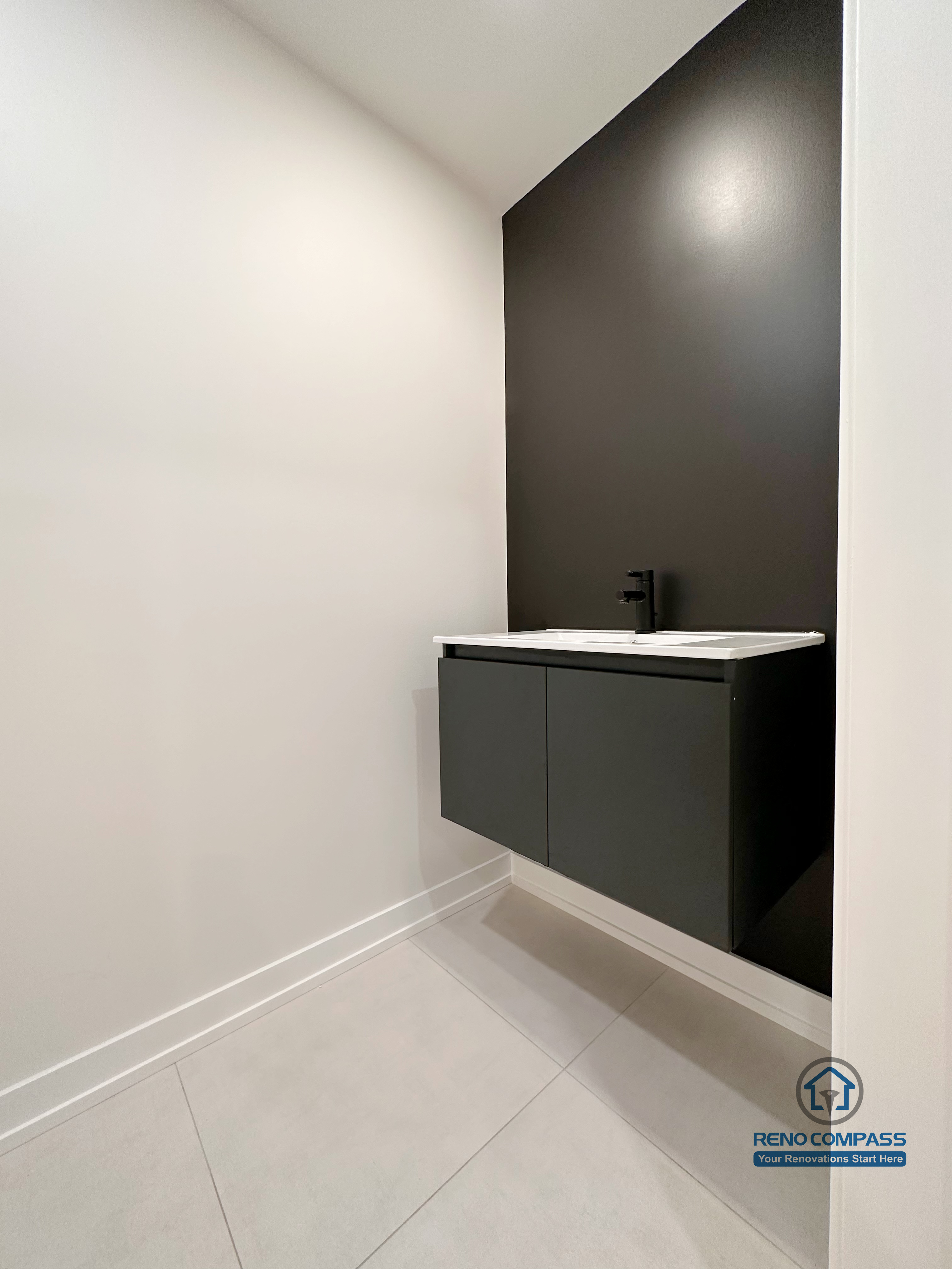 Minimalist bathroom renovation in Markham featuring a floating vanity, matte black fixtures, and a bold accent wall. The clean lines, neutral flooring, and compact layout create a modern powder room designed for functionality and visual impact.