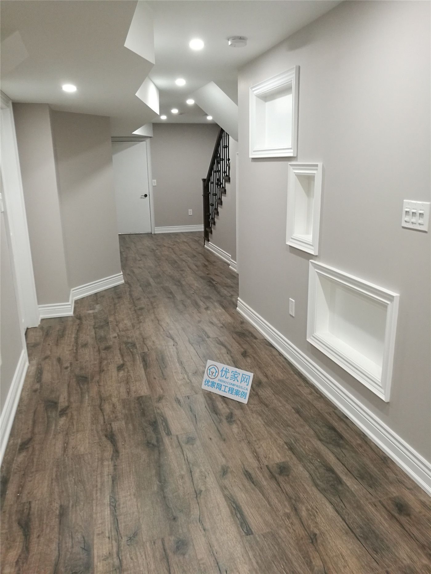This image highlights a completed Richmond Hill basement renovation, showcasing a finished basement hallway with upgraded wood-look flooring, recessed pot lighting, and custom wall detailing. The clean lines and neutral tones enhance the sense of space and brightness, improving overall flow and functionality. This basement renovation project was completed by a trusted Toronto renovation company, delivering high-quality craftsmanship for homeowners in Richmond Hill.
