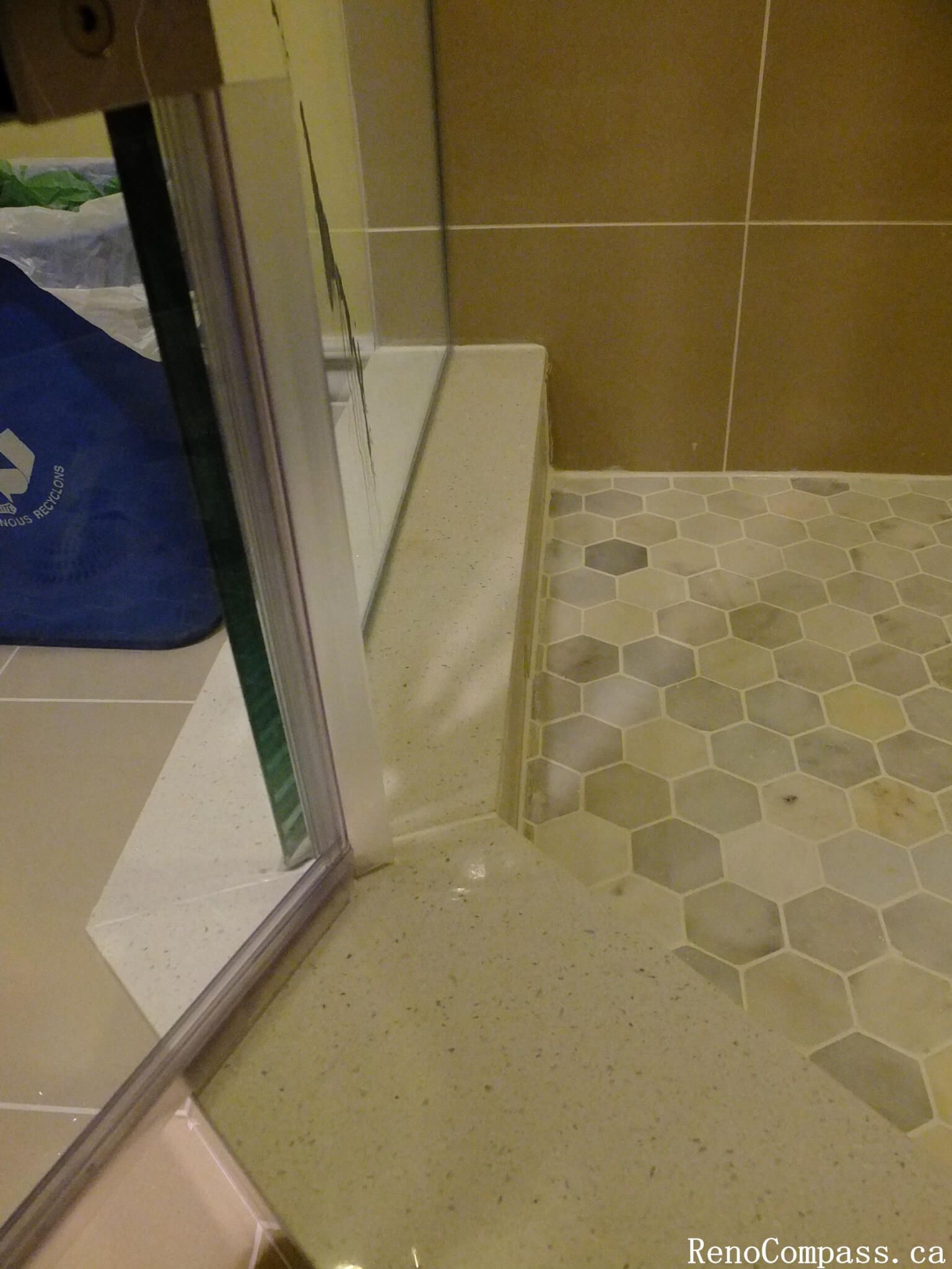 This Mississauga bathroom renovation features a detailed walk-in shower base with modern hexagon mosaic floor tiles. The geometric tile pattern adds texture and visual interest while providing slip resistance for improved safety. The shower is completed with a clean glass enclosure and a durable shower curb design that helps contain water effectively. Combined with neutral wall tiles and a modern layout, this shower floor installation highlights both functional design and refined finishing details in the bathroom renovation.
