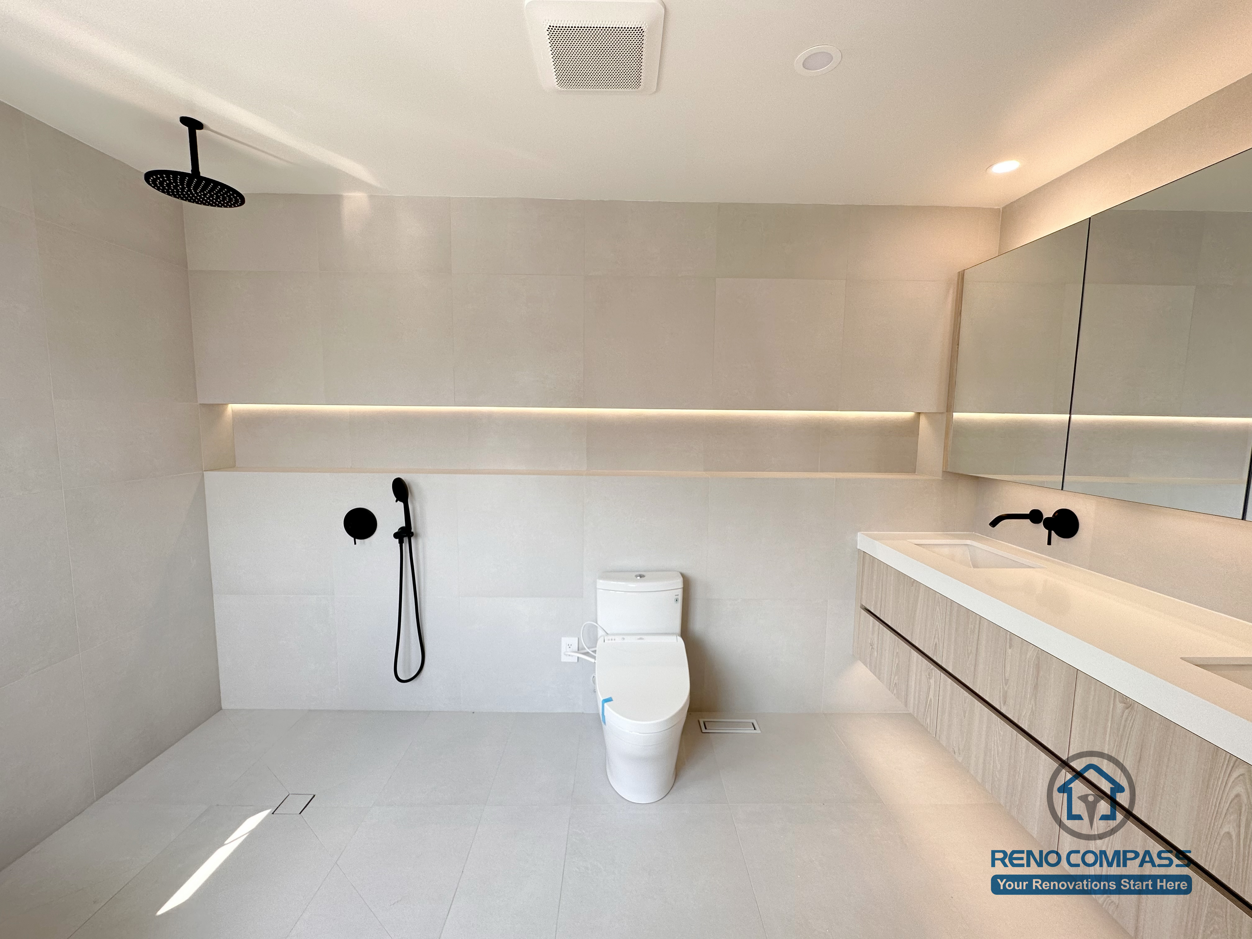 Open-concept bathroom renovation in Markham featuring a curbless walk-in shower, wall-mounted fixtures, floating vanity, and integrated ambient lighting. The minimalist layout improves accessibility, visual openness, and everyday comfort while maintaining a clean, modern aesthetic.