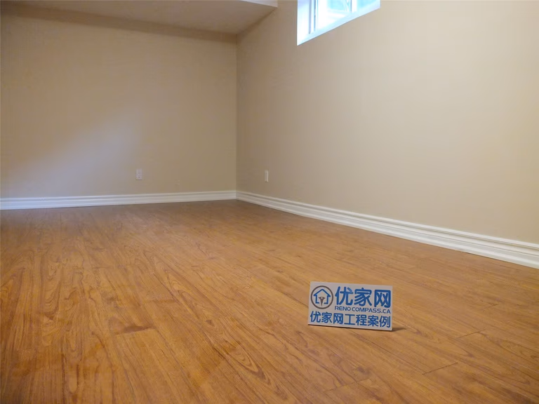 This Markham basement renovation project features newly finished walls, fresh interior painting, and durable laminate flooring installation. The clean wall finish, neutral paint tones, and wood-style flooring create a bright, comfortable living space suitable for a family recreation room or additional living area. Careful detailing around the baseboards and wall edges ensures a smooth and polished appearance throughout the basement interior.