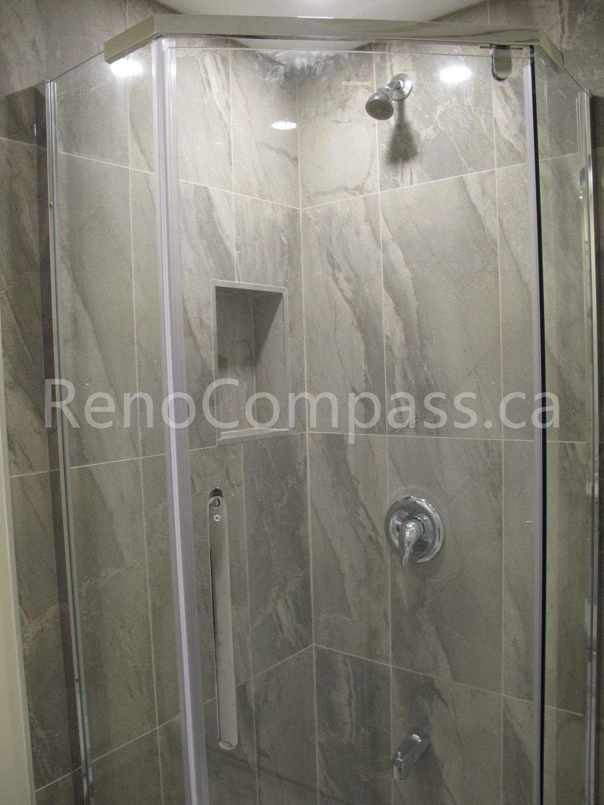 Modern glass shower enclosure installed in this Markham basement renovation, featuring marble-look wall tiles, built-in shower niche, and chrome fixtures. Completed by Reno Compass, this bathroom upgrade delivers a sleek, durable, and spa-inspired shower space for a fully finished basement living area.