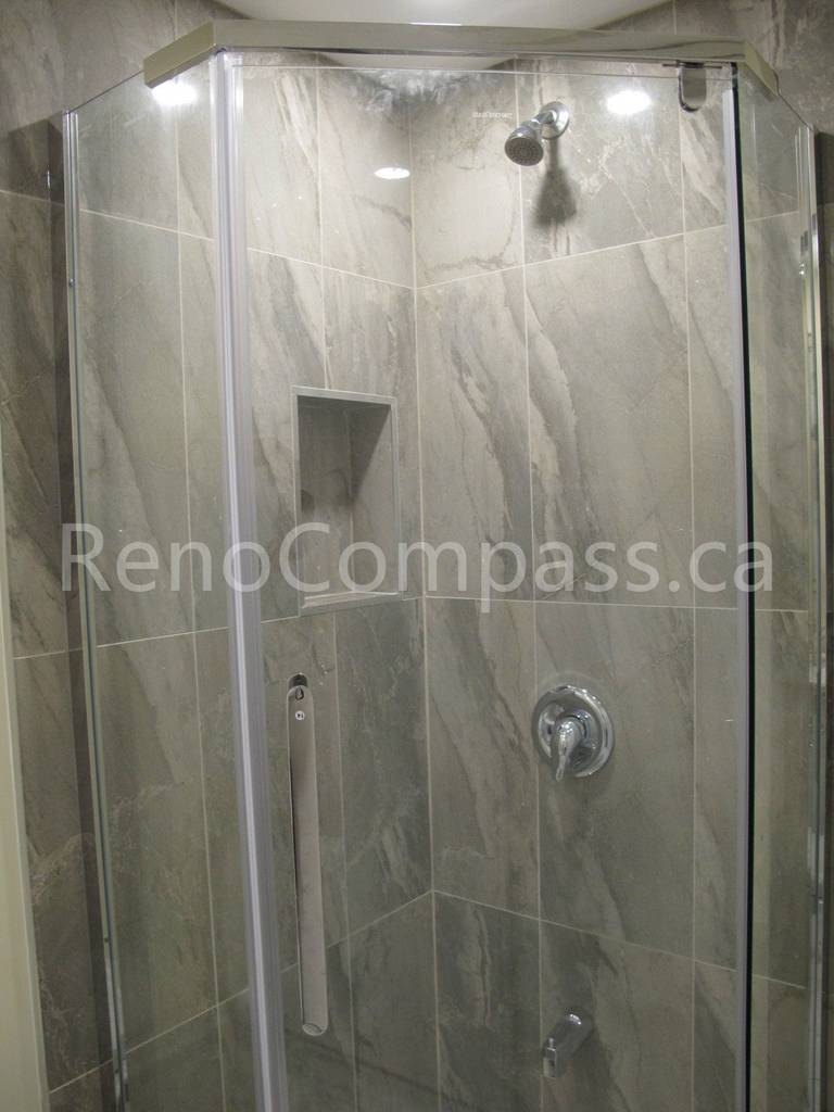 Modern glass shower enclosure installed in this Markham basement renovation, featuring marble-look wall tiles, built-in shower niche, and chrome fixtures. Completed by Reno Compass, this bathroom upgrade delivers a sleek, durable, and spa-inspired shower space for a fully finished basement living area.