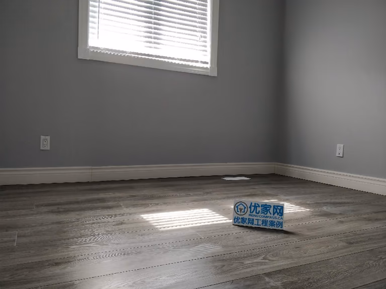 Bedroom interior renovation in Ajax featuring durable grey vinyl plank flooring, freshly painted walls, and updated white interior doors and baseboards. The modern flooring upgrade enhances the room’s brightness and functionality, completed by a professional Toronto renovation company specializing in residential interior improvements.