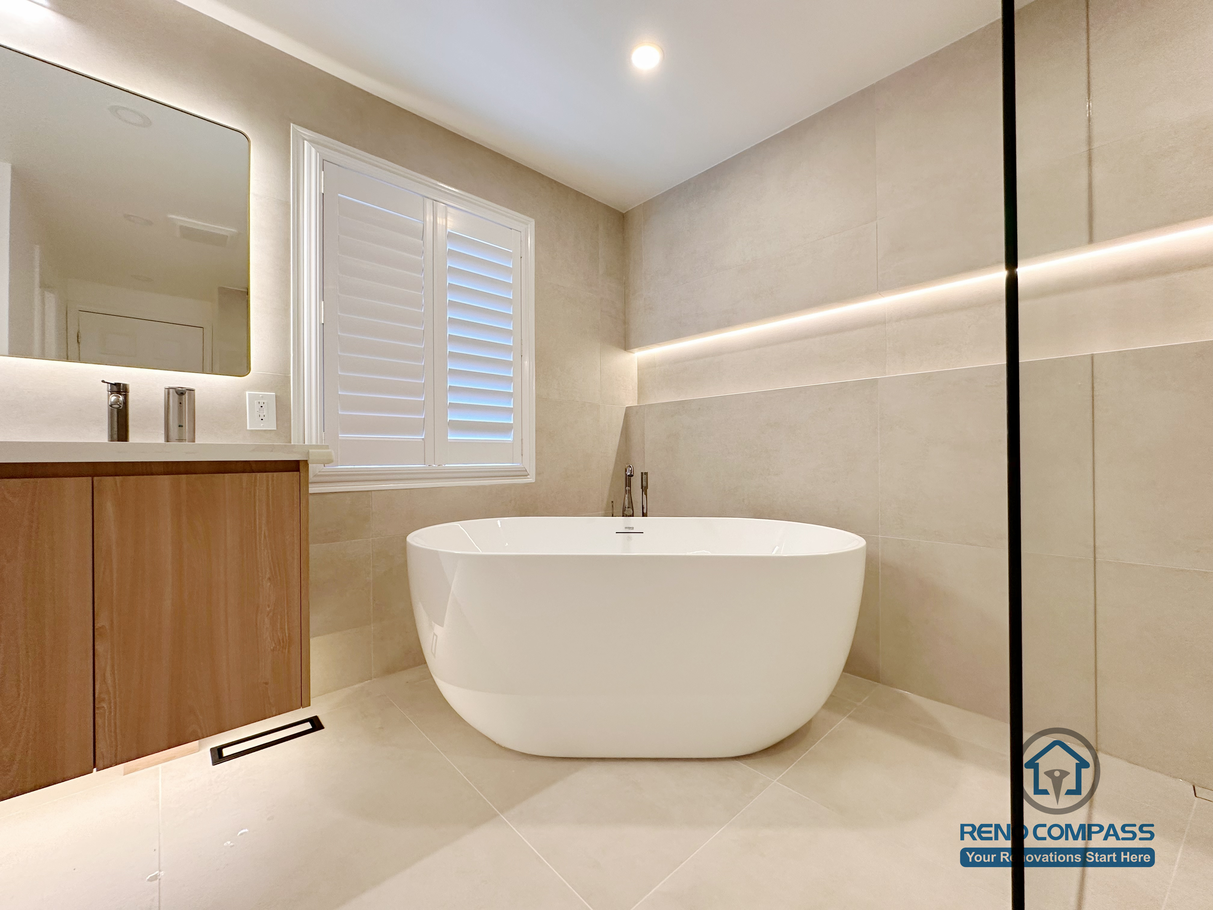This Markham accessible bathroom renovation features a freestanding bathtub positioned within a barrier-free layout, allowing easy movement and step-free access. Large-format floor and wall tiles, integrated linear lighting, and a custom wood-tone vanity contribute to a calm, safe, and modern environment. Designed and built by a professional Toronto renovation company, Reno Compass Inc., the space prioritizes accessibility, comfort, and long-term usability.