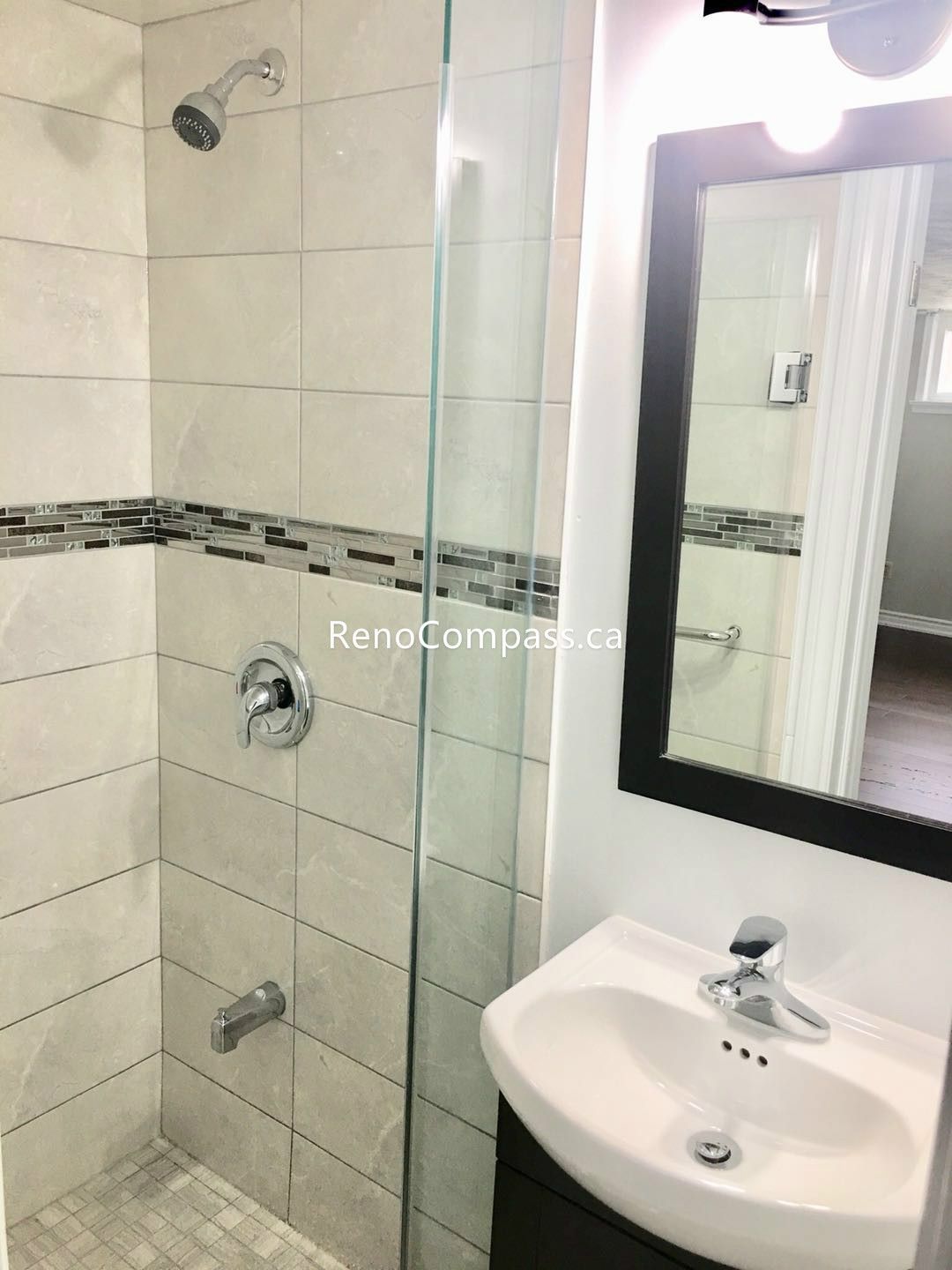This Toronto basement renovation features a newly upgraded bathroom with a modern glass shower enclosure, elegant wall tiles, and a compact contemporary vanity. The neutral tile tones and clean finishes create a bright, functional, and stylish bathroom perfect for basement living. Completed by Reno Compass Inc., this basement bathroom renovation enhances comfort, practicality, and property value with quality craftsmanship and modern design.