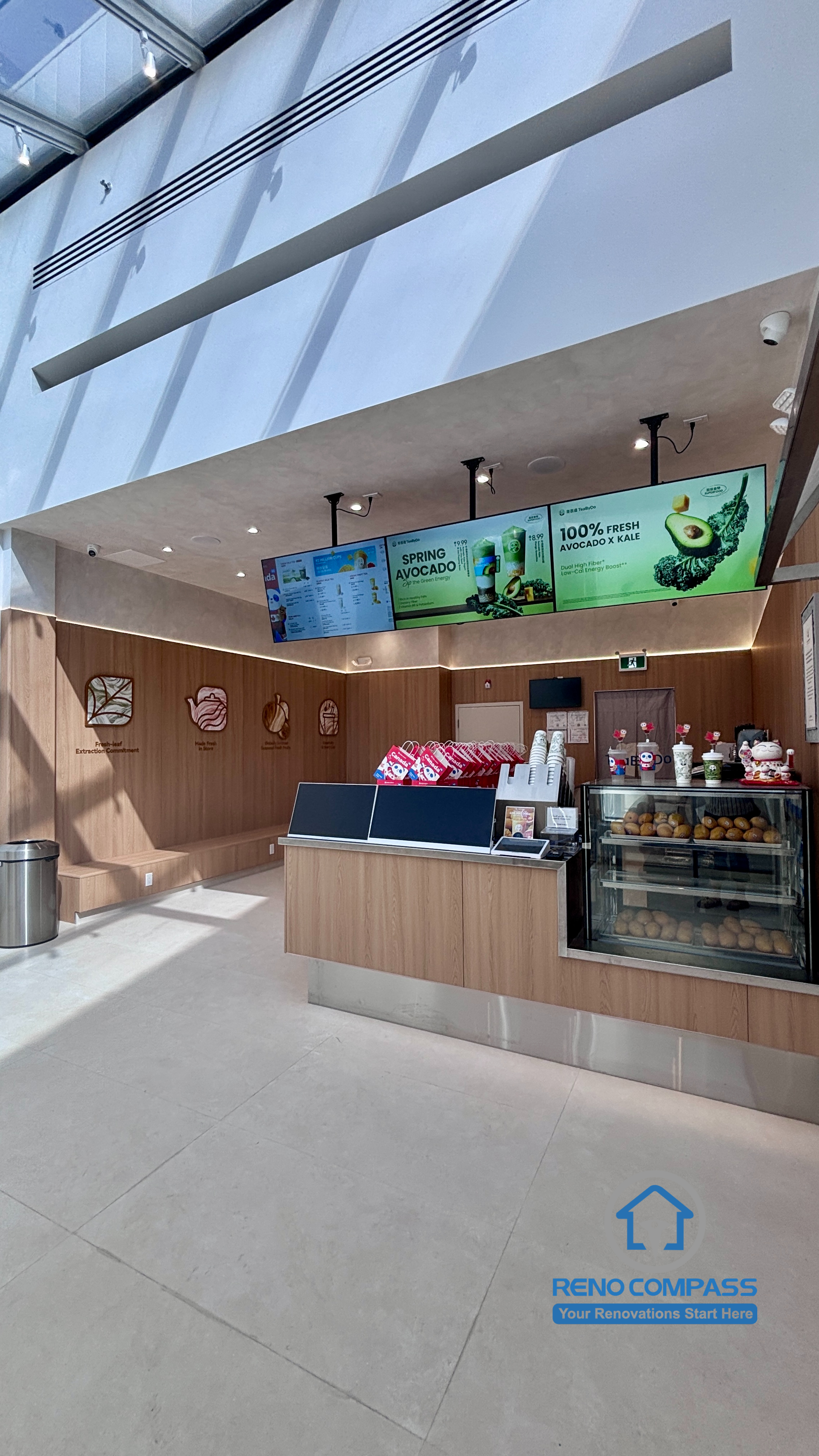 Completed TEABYDO bubble tea shop renovation in Richmond Hill featuring a bright skylight café interior, custom front service counter, beverage display fridge, digital menu boards, wood-tone commercial finishes, and clean minimalist customer-focused layout. Commercial renovation project completed by Reno Compass serving Richmond Hill, Toronto, and the GTA.