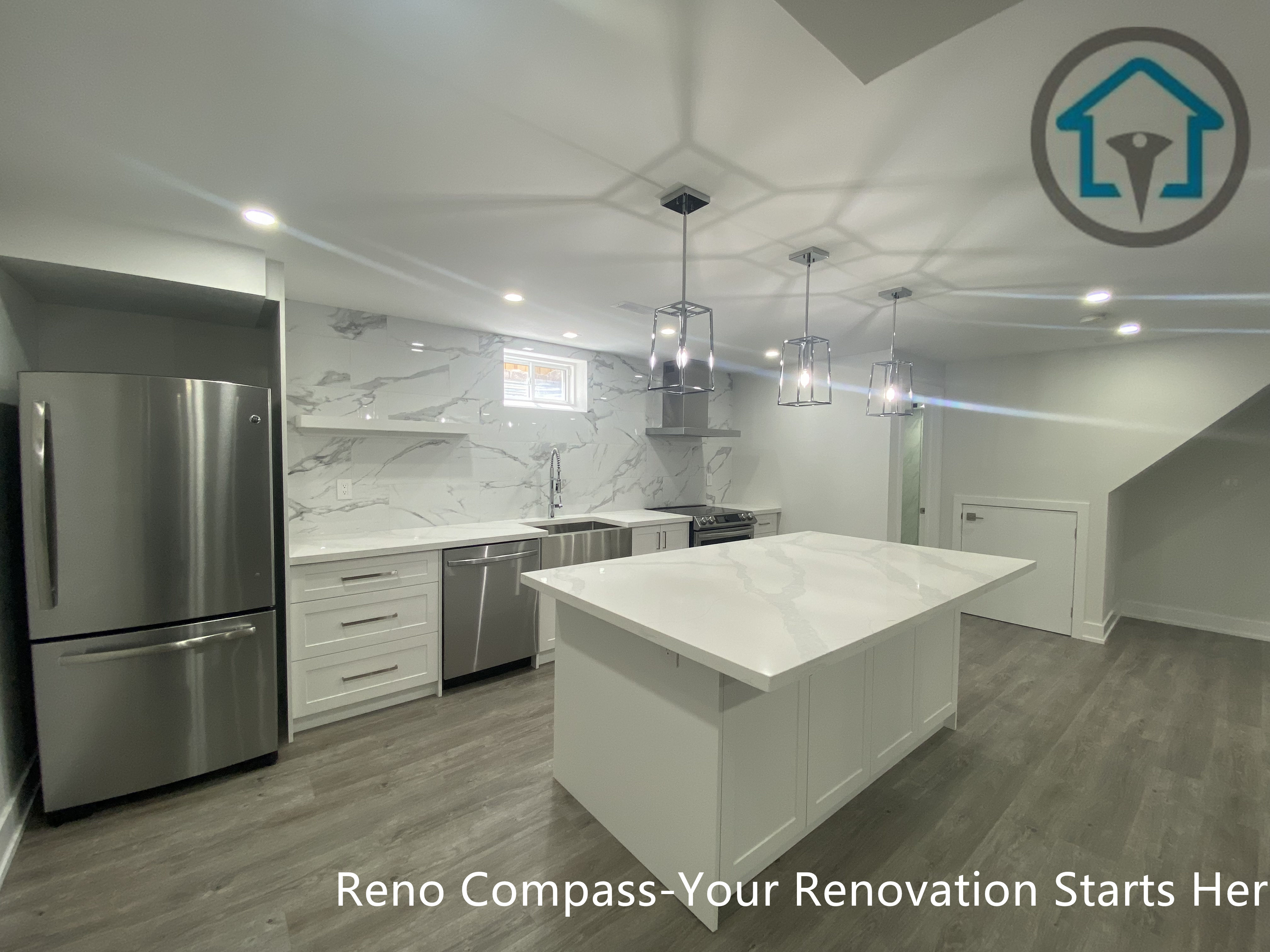 This image features a modern basement kitchen renovation in Newmarket completed by an experienced Toronto renovation company. The design centers around a large quartz island with shaker-style cabinetry, complemented by stainless steel appliances, marble-look backsplash, and contemporary pendant lighting. Recessed ceiling lights and neutral finishes enhance brightness and functionality, making the basement kitchen ideal for daily use, entertaining, or rental purposes.