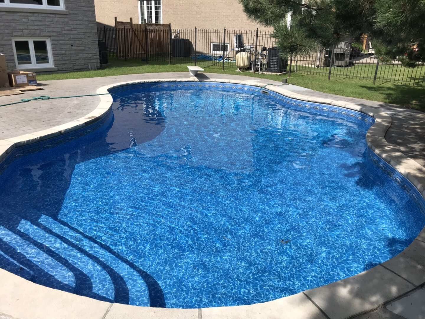 After renovation photo of a fully restored backyard swimming pool in Toronto. The new bright blue liner, clean water, and resurfaced edges highlight the professional pool transformation from old and damaged to modern and inviting. Expert pool renovation by local Toronto specialists.