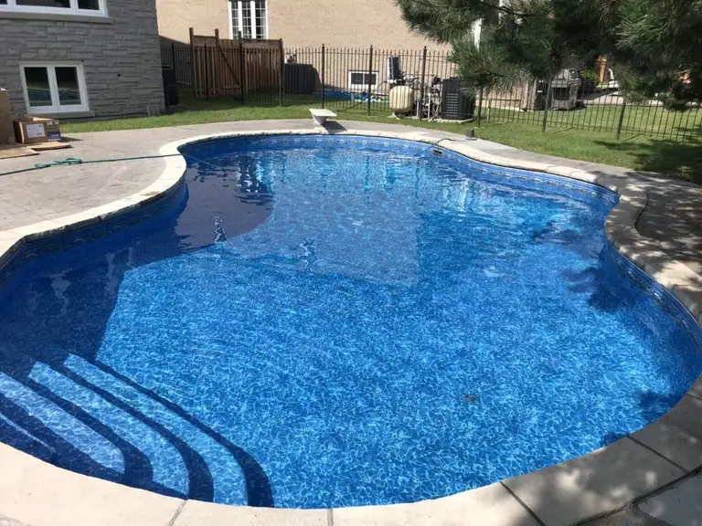 After renovation photo of a fully restored backyard swimming pool in Toronto. The new bright blue liner, clean water, and resurfaced edges highlight the professional pool transformation from old and damaged to modern and inviting. Expert pool renovation by local Toronto specialists.