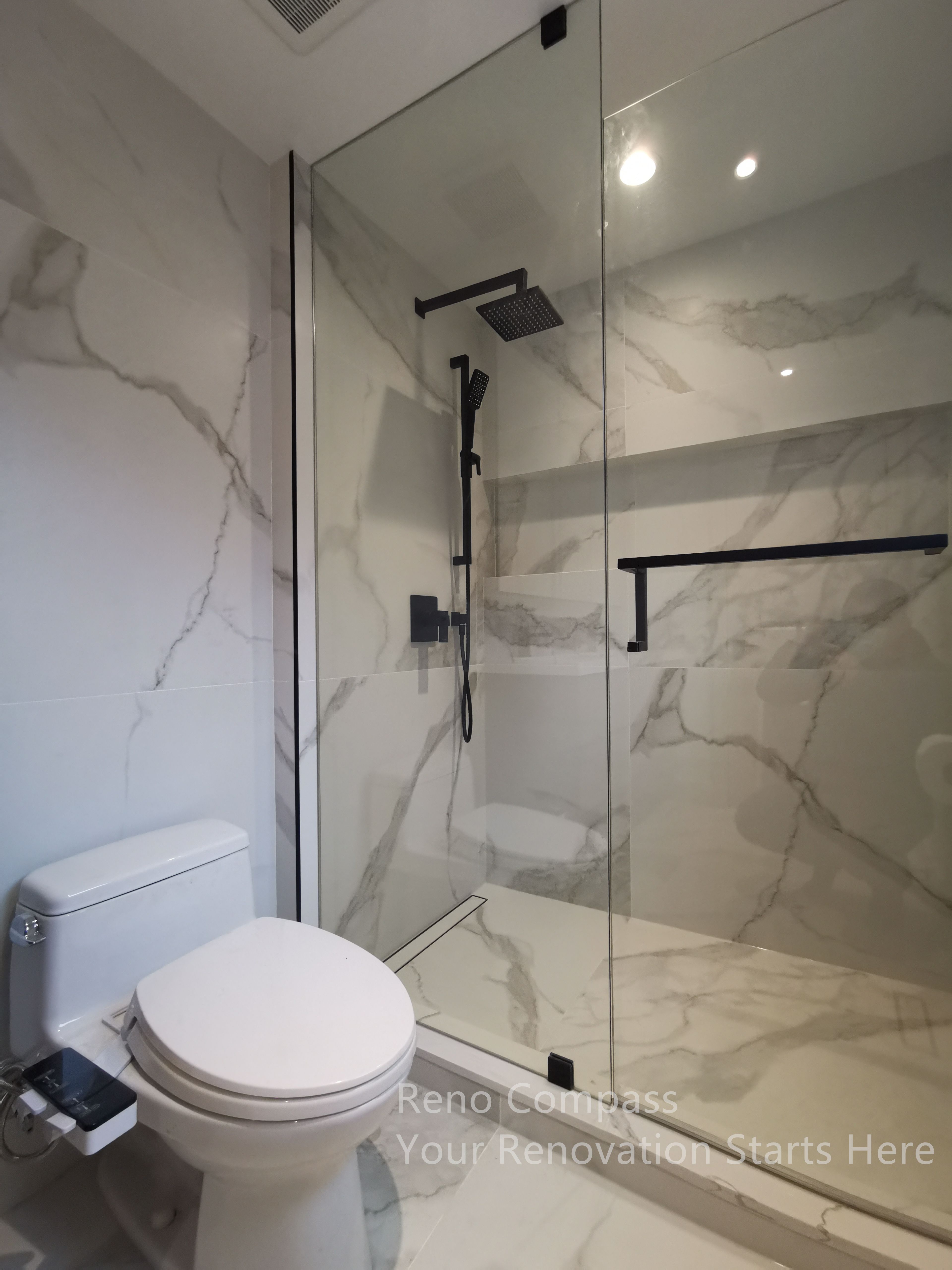 This image showcases a modern walk-in shower completed as part of a Markham interior renovation. Large-format marble-style wall tiles create a seamless and spacious visual effect, while the frameless glass enclosure enhances openness and light flow. Matte black shower fixtures and hardware provide strong contrast against the neutral surfaces, combining contemporary aesthetics with durable, easy-to-maintain materials for everyday use.