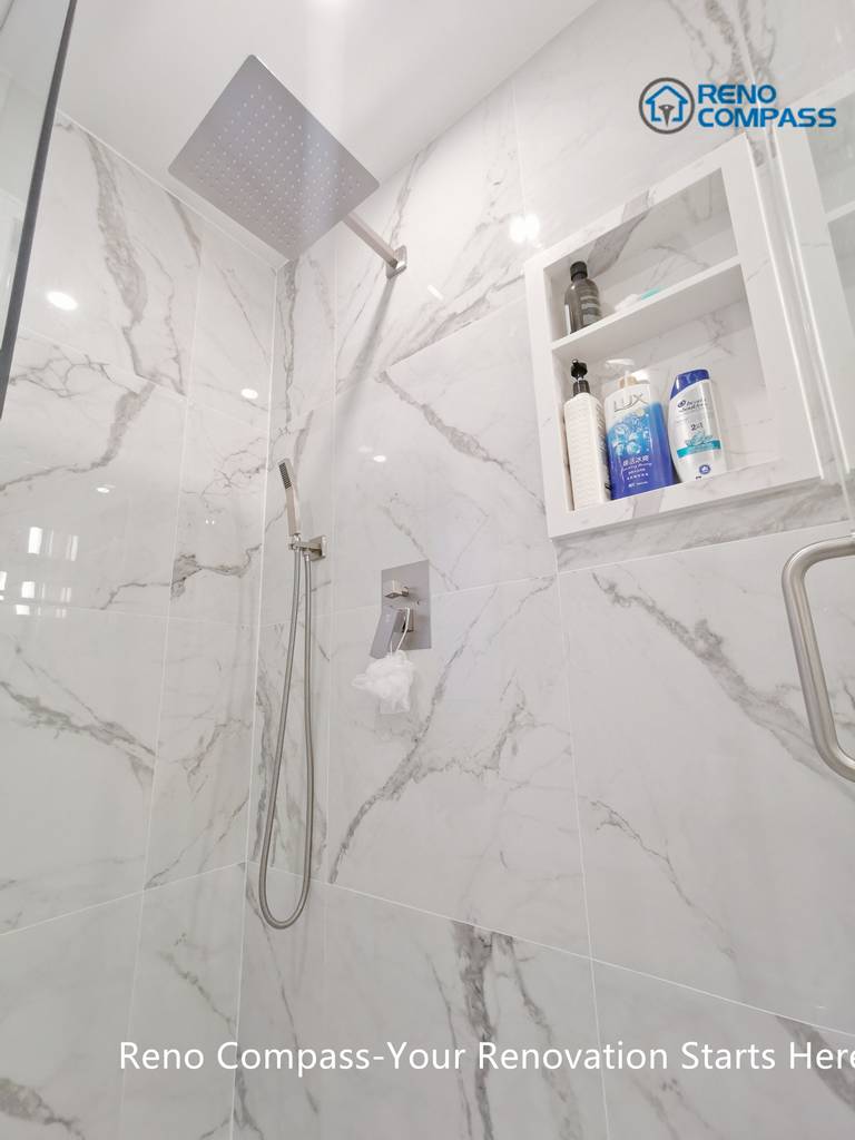 This Mississauga bathroom renovation highlights a frameless walk-in shower finished with large-format marble-look porcelain tiles. A ceiling-mounted rain shower head, handheld fixture, and built-in wall niche improve everyday comfort while maintaining a clean, minimalist appearance. The recessed storage niche enhances functionality without interrupting the visual flow of the space. Precision tile installation and thoughtful detailing reflect the quality standards expected from a professional Toronto renovation company.