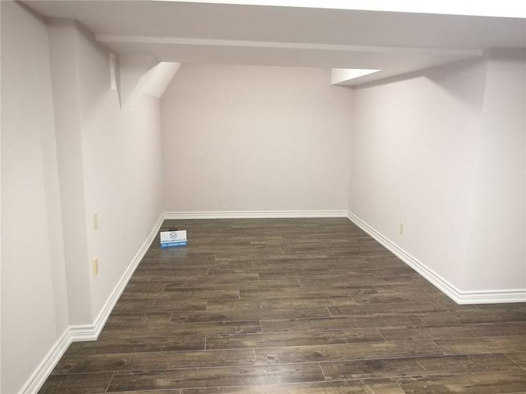 This image shows a completed basement area as part of a Markham basement renovation project. The space features durable vinyl plank flooring, freshly painted neutral walls, and clean white baseboard detailing. The simple rectangular layout allows for flexible use as a family room, home office, storage area, or recreation space. Low-profile ceiling beams are neatly finished to maintain headroom while ensuring structural integrity. This renovation highlights the practical design and quality workmanship delivered by a professional Toronto Renovation Company.