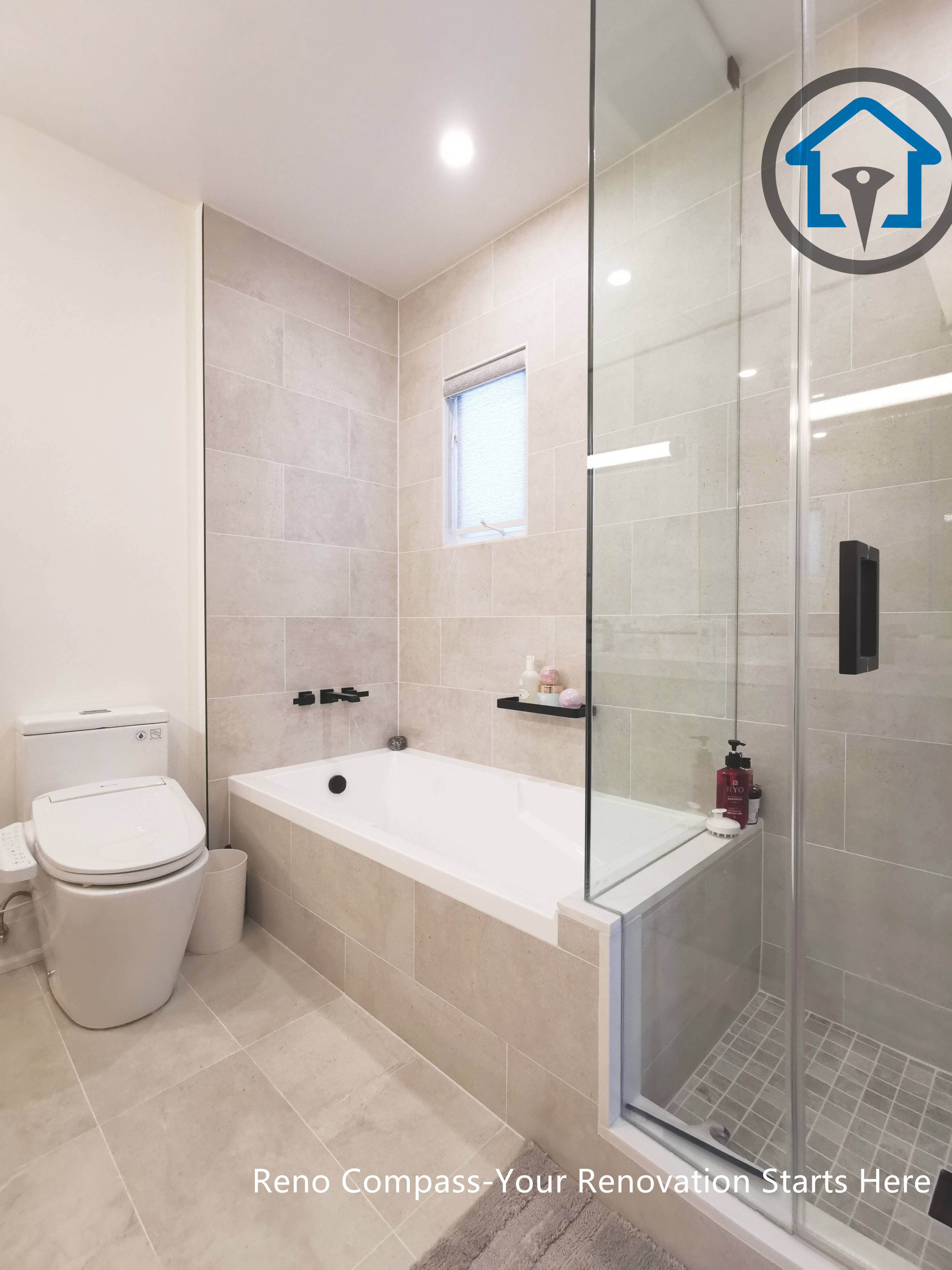 This North York bathroom renovation features a clean and modern layout with a built-in bathtub, glass-enclosed shower, and light-toned tile finishes. Matte black fixtures provide subtle contrast, while the window improves natural light and ventilation. Completed by a Toronto renovation company focused on durable materials, clear layouts, and long-term bathroom performance.