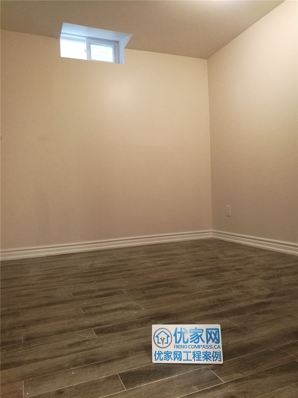 This image features a completed basement renovation project in Markham, showcasing a clean and functional finished basement space. Light-colored walls paired with durable wood-look flooring create a warm and modern atmosphere. A high-set window allows natural light to enter while maintaining privacy, making the space ideal for a home office, recreation room, or guest area. Completed by a professional Toronto Renovation Company, this basement renovation focuses on moisture-resistant materials, improved lighting, and practical layout planning to maximize everyday usability and long-term value.