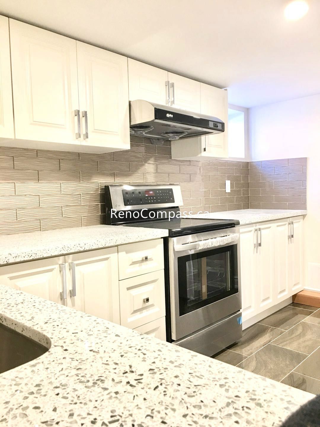 This Toronto basement renovation features a fully upgraded basement kitchen with modern white shaker cabinets, quartz countertops, stainless steel stove, and stylish textured backsplash. The functional layout maximizes storage and cooking space while maintaining a bright, contemporary design. Completed by an experienced Toronto renovation company, this basement kitchen enhances comfort, usability, and property value with quality craftsmanship and durable materials.