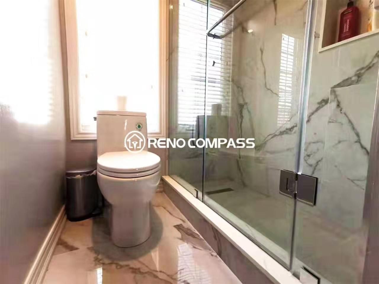 Bright and modern bathroom renovation featuring a frameless glass shower enclosure, marble-look flooring, and a clean toilet layout beside a large window for natural light. Designed and completed by a professional Toronto renovation company, this upgrade focuses on efficient space planning, waterproof tile installation, and durable finishes that enhance both comfort and long-term functionality.