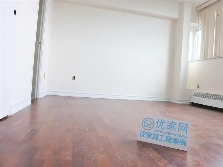 A bright and refreshed condo interior in Scarborough featuring newly installed flooring and clean white walls. This open living space benefits from large windows that enhance natural light, creating a warm and comfortable atmosphere. The renovation improves overall functionality and visual appeal, showcasing professional interior renovation work by a Toronto renovation company.