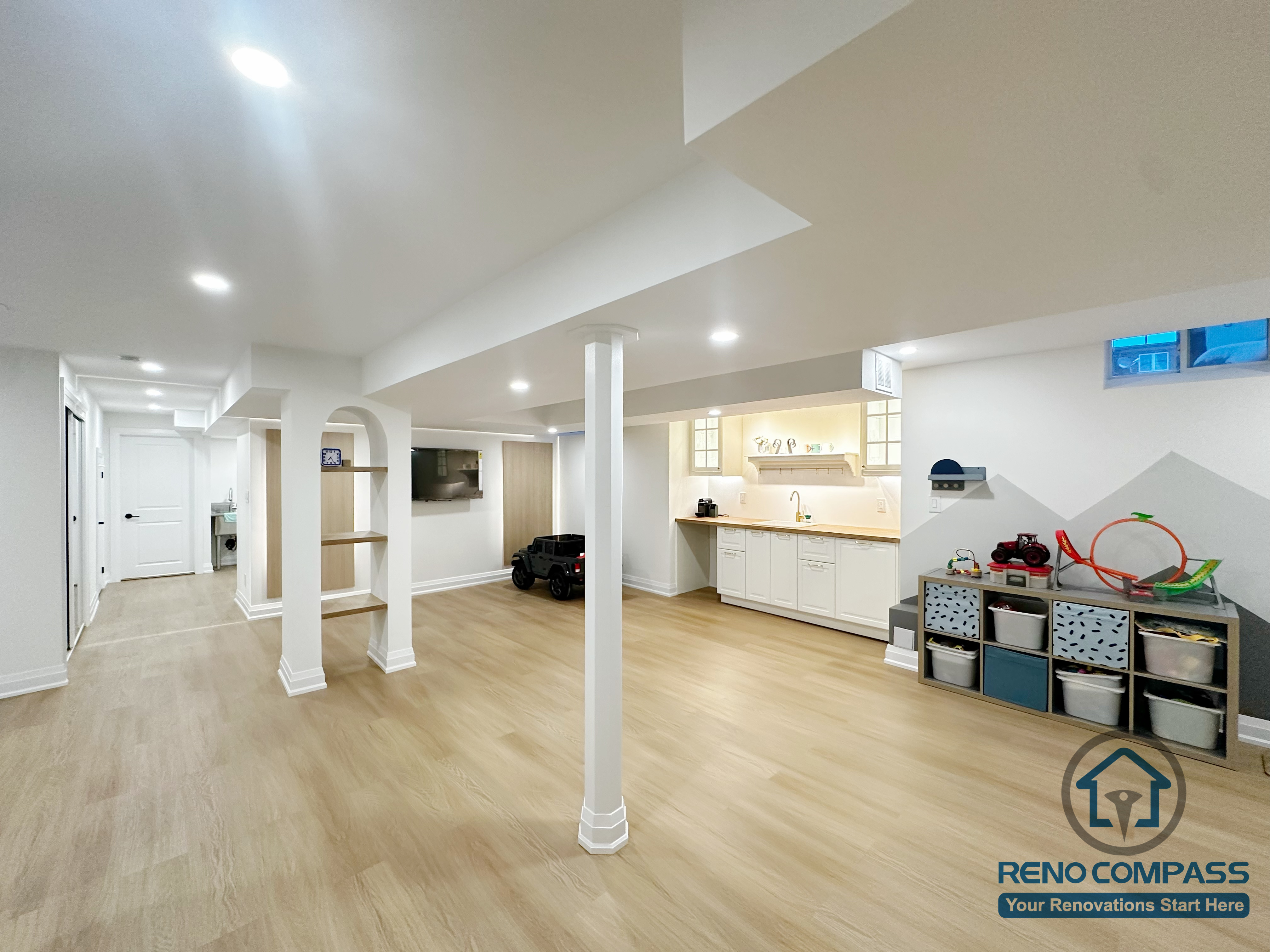Open-concept basement renovation in Markham featuring light wood flooring, recessed ceiling lighting, and clean white support columns. The layout improves brightness, structural clarity, and flexibility for family living, recreation, and future customization.