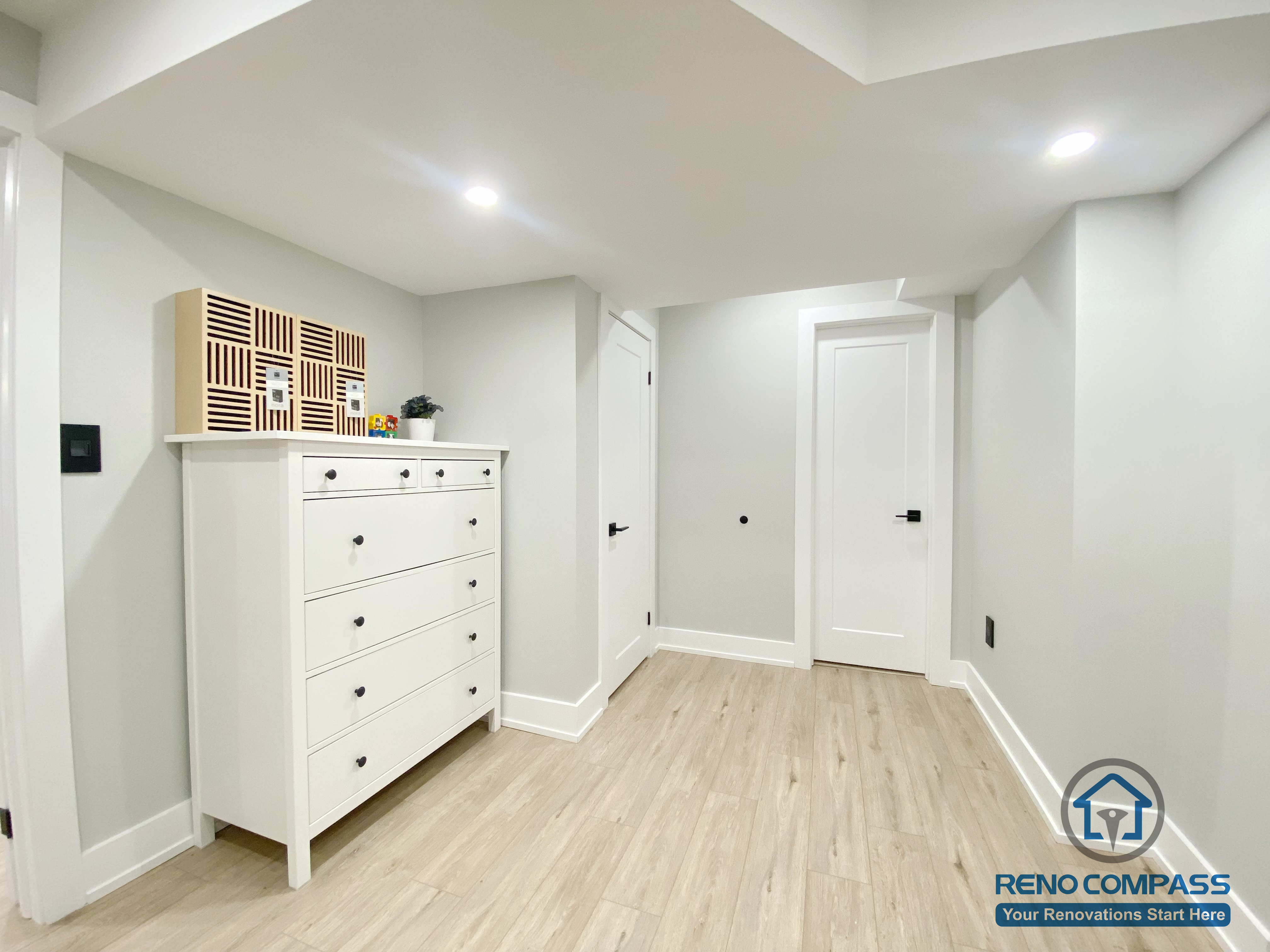 This Aurora basement renovation includes a clean and functional hallway and storage area designed for everyday practicality. The space features wood-look flooring, smooth neutral wall finishes, recessed ceiling lighting, and built-in storage furniture that enhances organization without compromising visual simplicity. Completed by a Toronto renovation company, this basement renovation demonstrates thoughtful attention to circulation, storage solutions, and overall usability in lower-level living spaces.