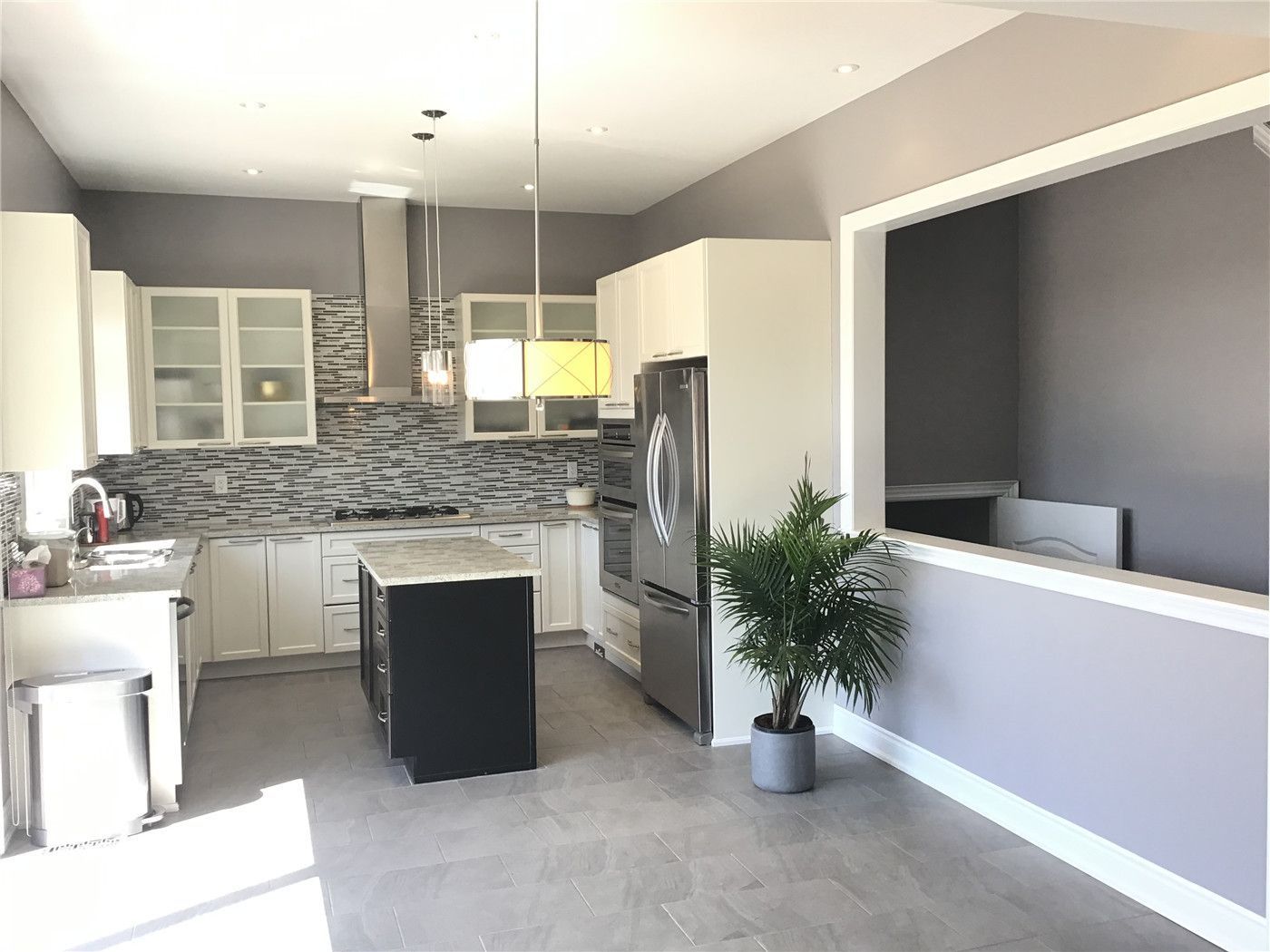 This Markham full home renovation showcases a modern kitchen with white cabinetry, a functional center island, and a stylish mosaic backsplash. The open-concept layout, stainless steel appliances, and ample natural light create a bright and efficient cooking space. Completed by a trusted Toronto Renovation Company, this kitchen design combines practicality with contemporary elegance.