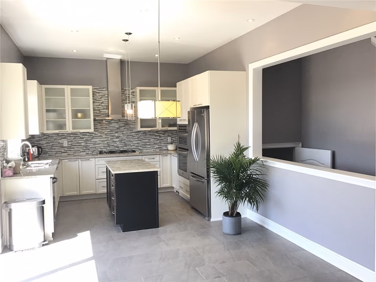 This Markham full home renovation showcases a modern kitchen with white cabinetry, a functional center island, and a stylish mosaic backsplash. The open-concept layout, stainless steel appliances, and ample natural light create a bright and efficient cooking space. Completed by a trusted Toronto Renovation Company, this kitchen design combines practicality with contemporary elegance.
