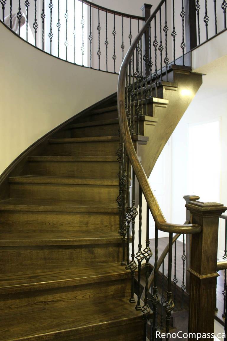 This Mississauga interior renovation features a stunning curved hardwood staircase with custom iron railing and detailed wood craftsmanship. The upgraded staircase enhances both safety and visual impact, creating a grand focal point within the home. Completed by a professional Toronto renovation company, Reno Compass Inc., this project highlights precision workmanship, elegant design, and high-quality interior finishing.
