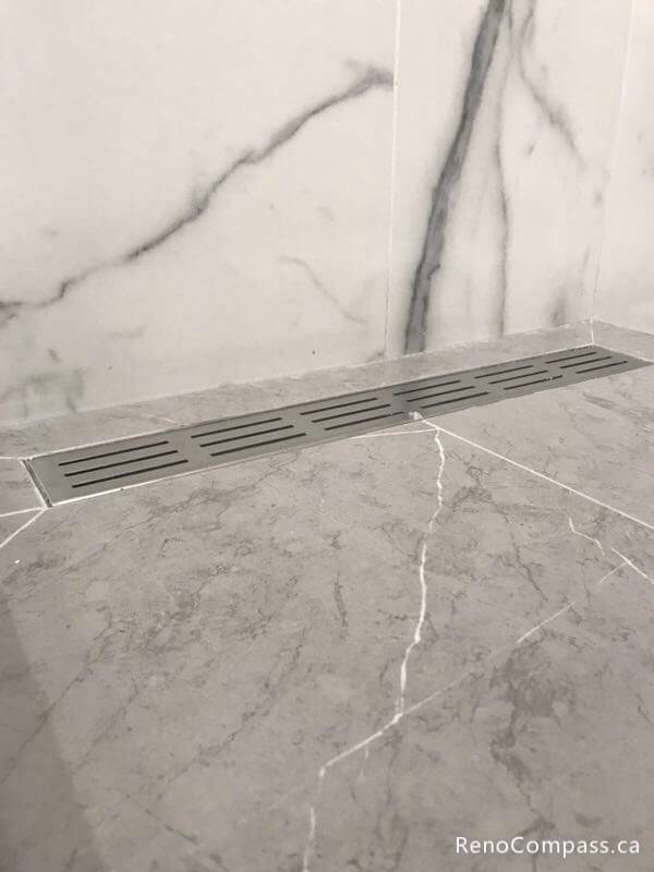 Precision tile installation and modern drainage solutions in a Markham master bathroom. Featuring high-end marble-style finishes and expert waterproofing for a luxury walk-in shower.